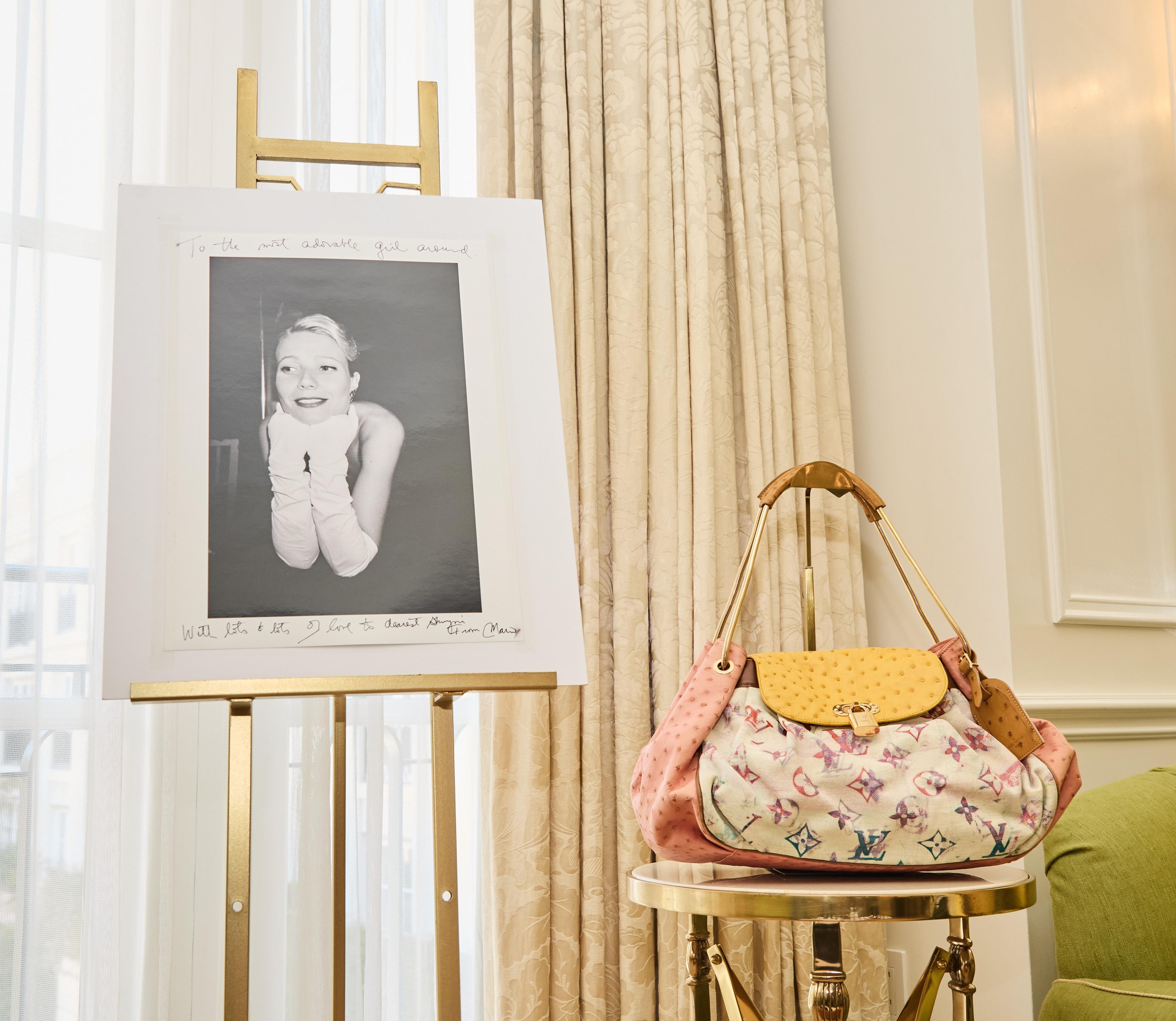 louis vuitton handbag on a table next to a photo of gwyneth paltrow
