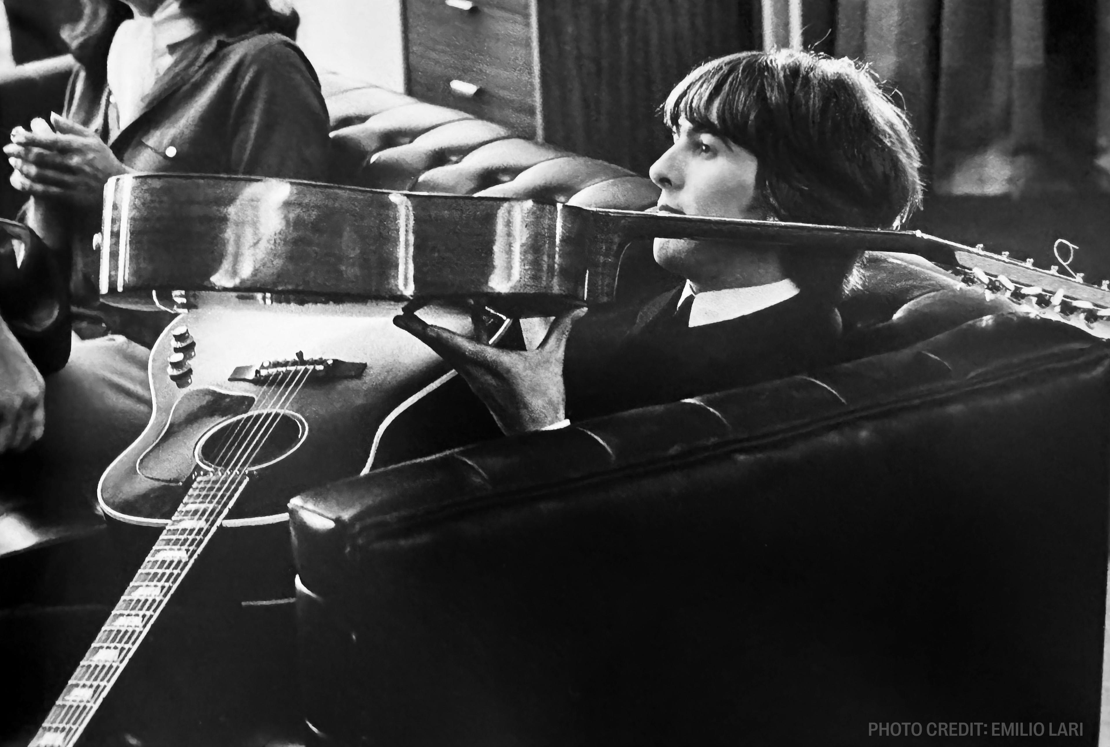 a man is sitting on a couch holding an acoustic guitar .