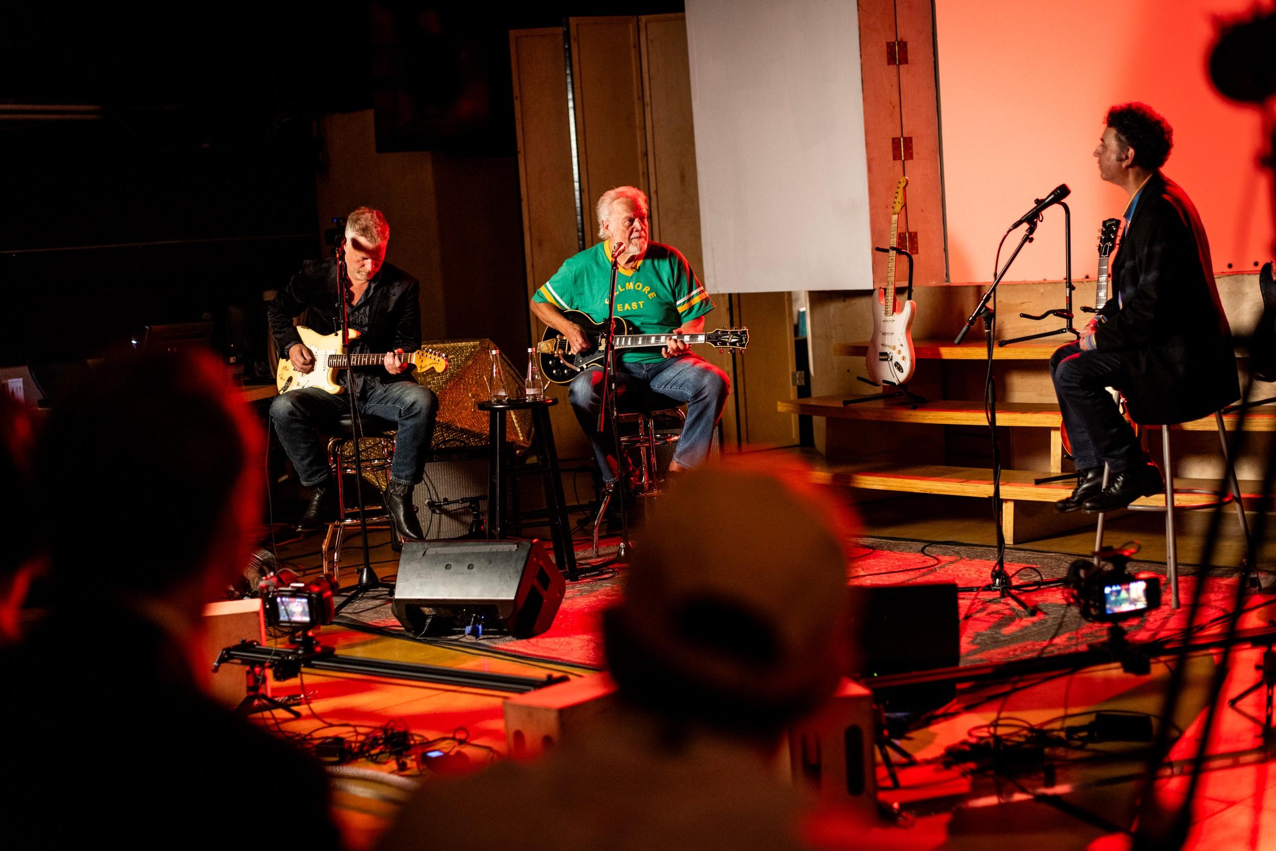 a group of men are playing guitars and singing on a stage .