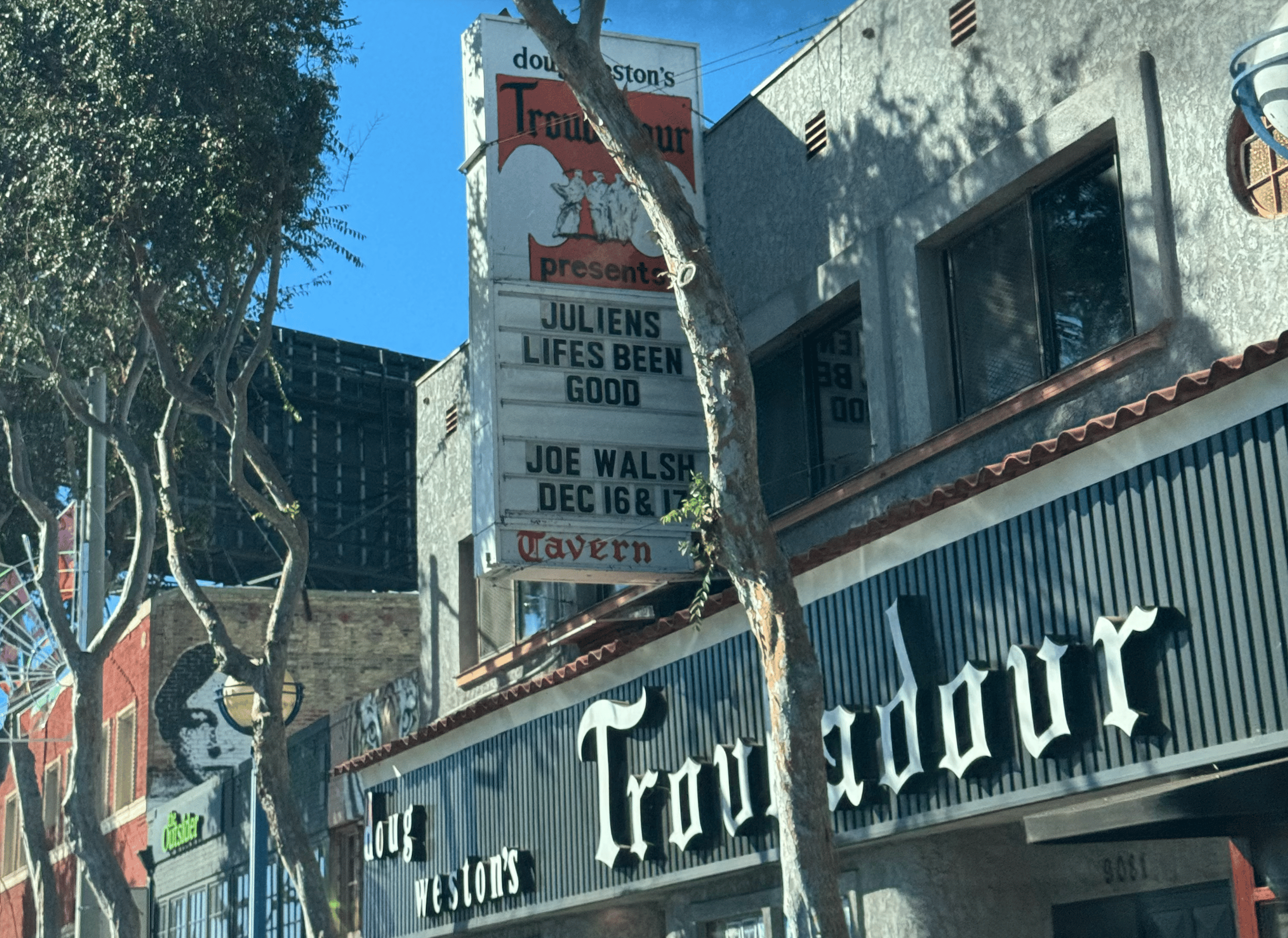The Troubadour music venue, with its vertical sign listing Joe Walsh shows and a large sign spelling "Troubadour" on the building facade.