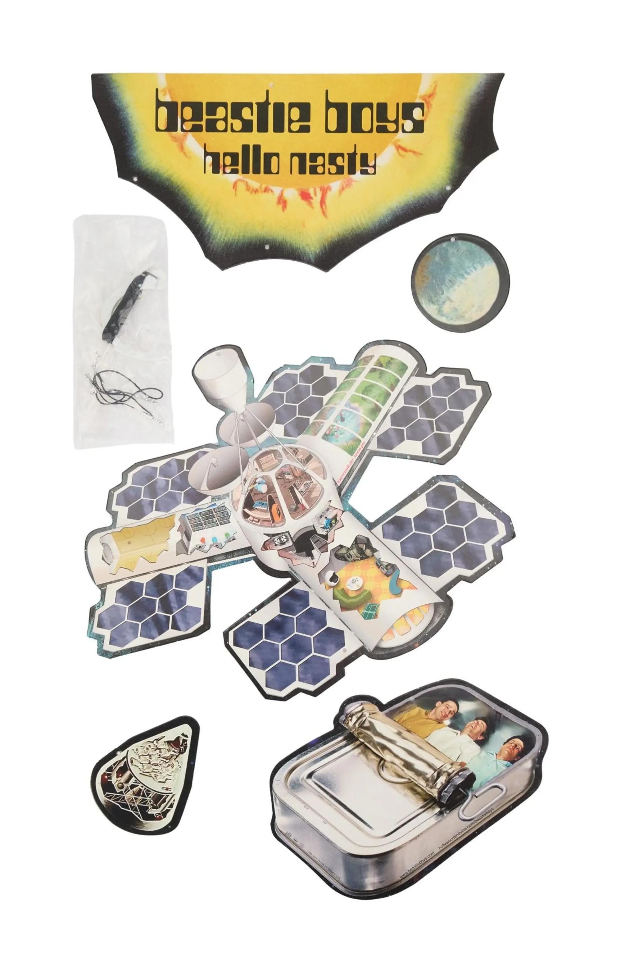 A collection of Beastie Boys 'Hello Nasty' promotional items, including a space station cutout, a sardine can with band members, and a logo banner.