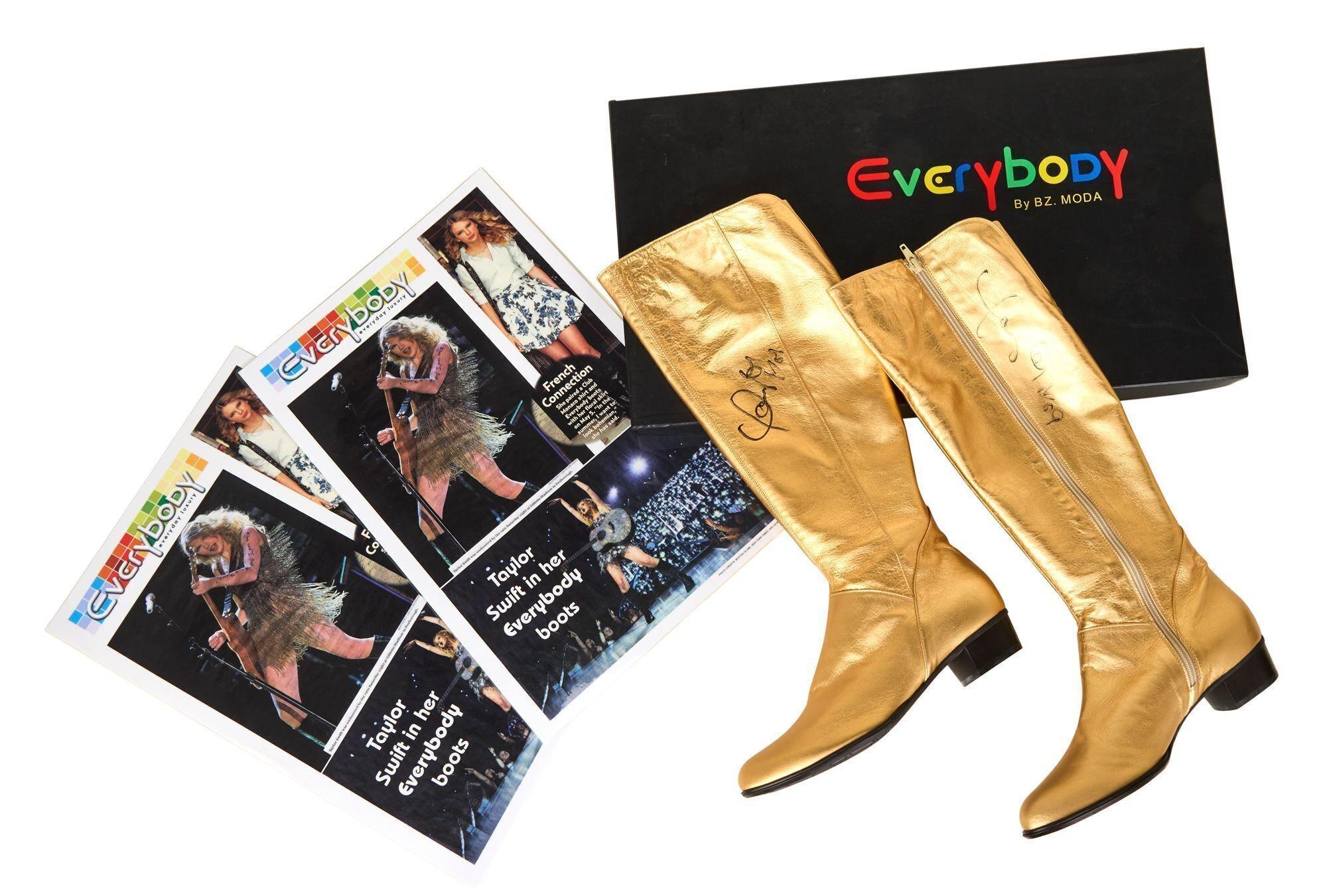 a pair of gold boots are sitting next to a magazine and a box .
