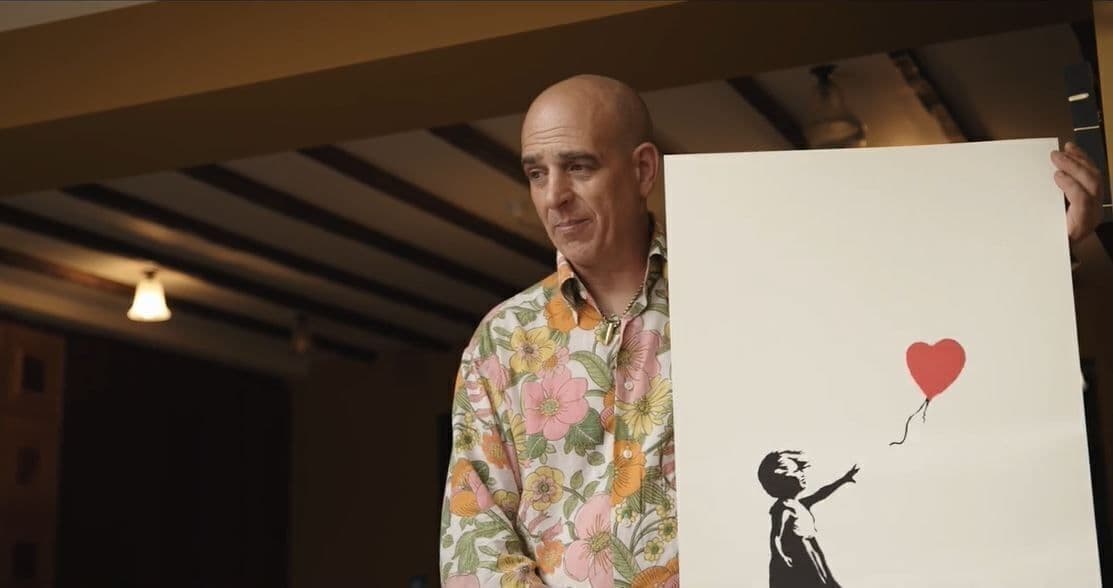 Steve Lazarides holds an original banksy artwork