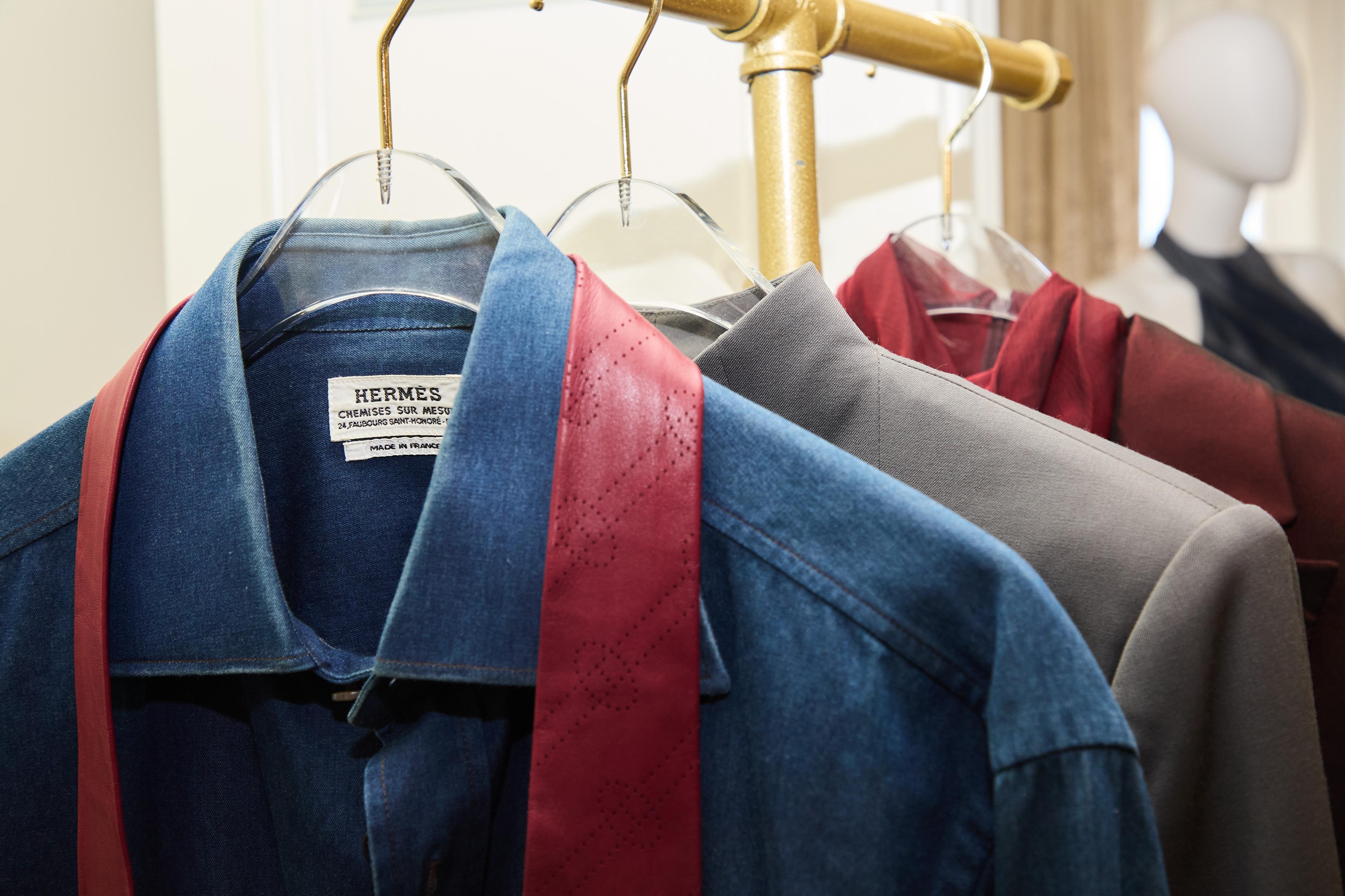 an hermes denim shirt on a hanger with other dress shirts