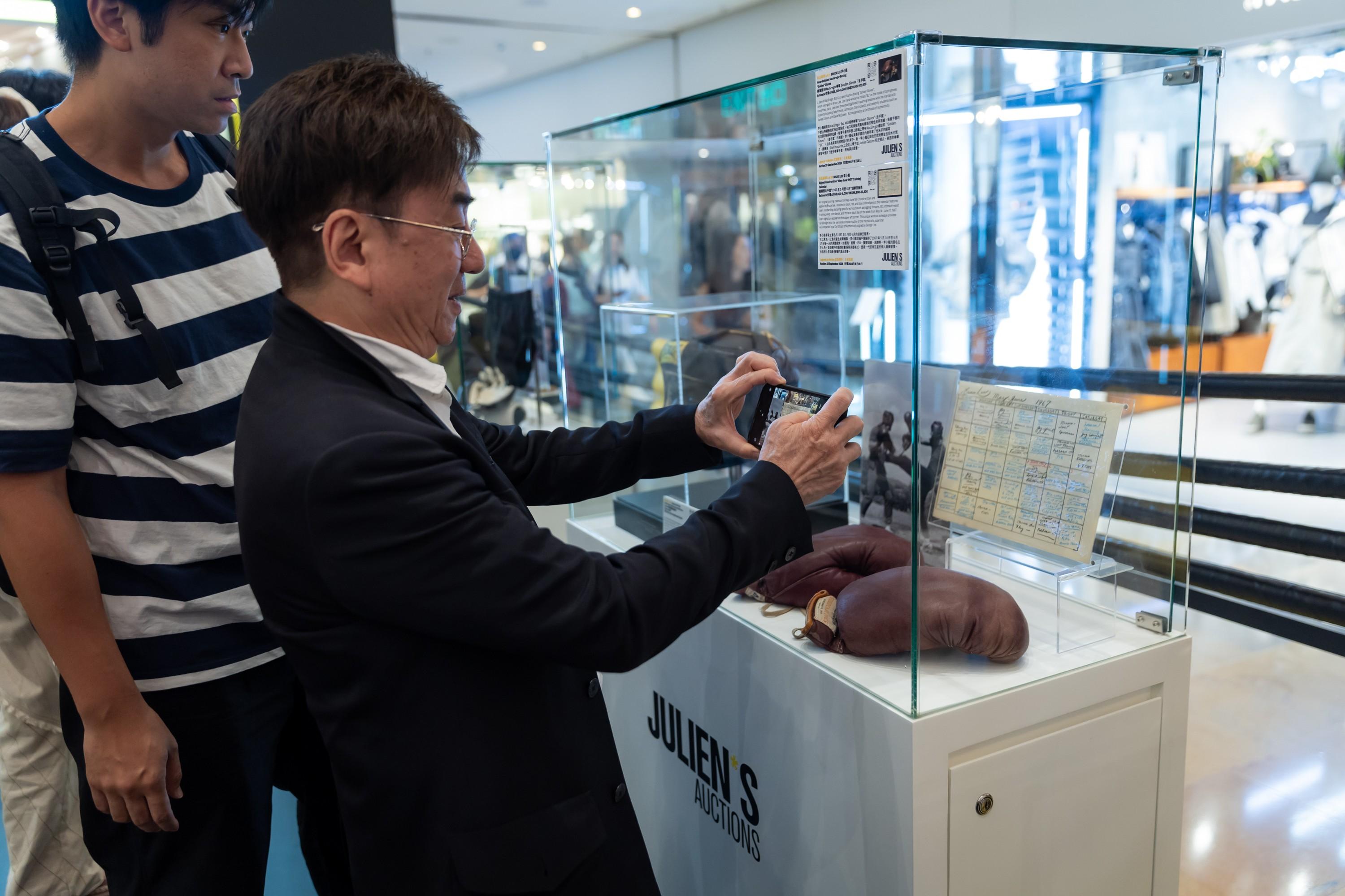 a man is taking a picture of a display case with a cell phone .