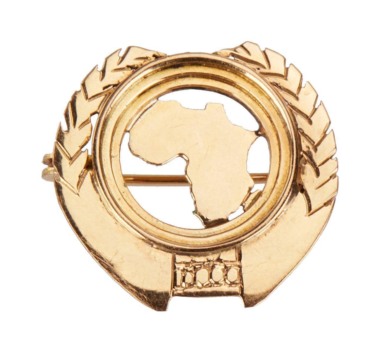 a gold brooch with a map of africa in the center