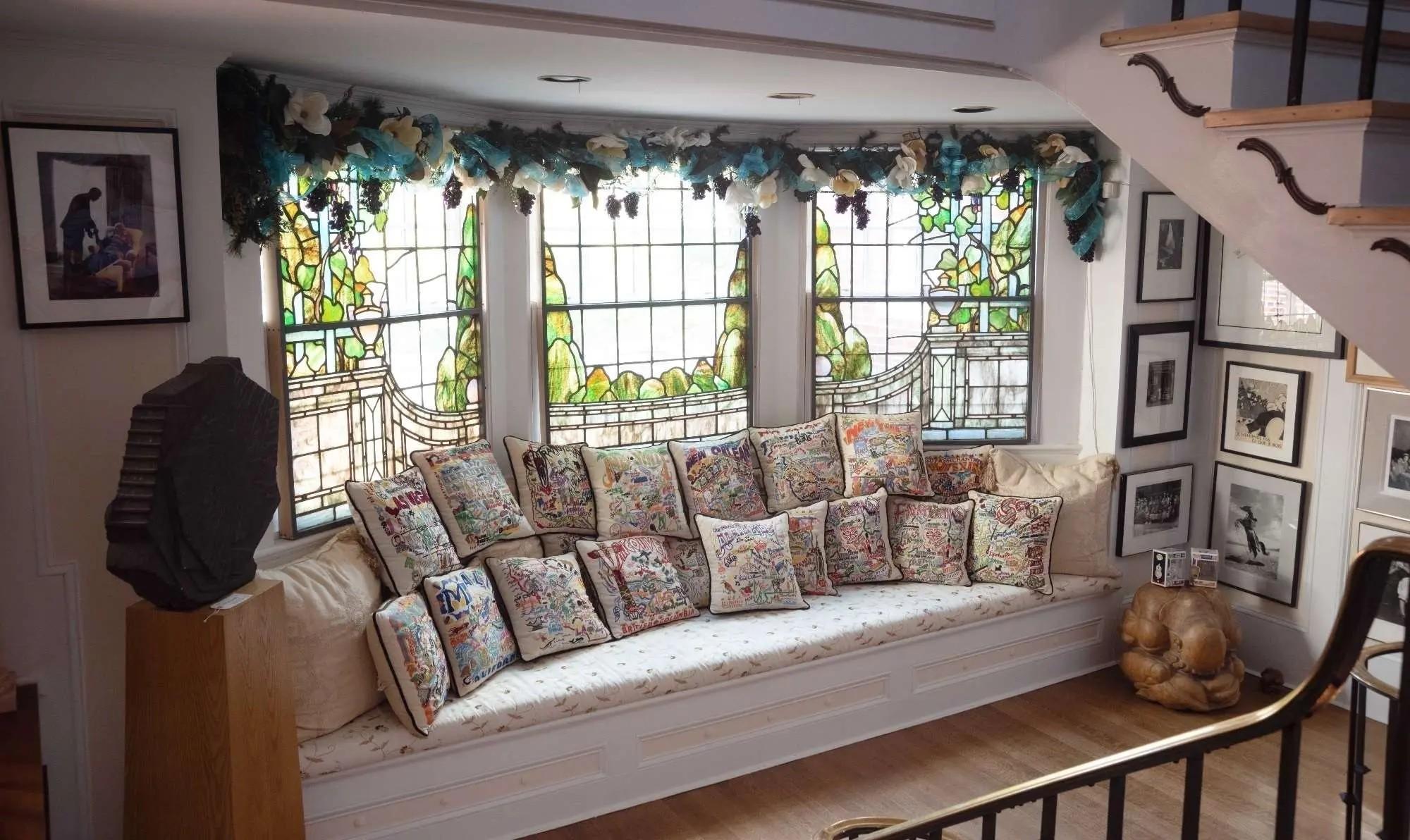 a large bay stained glass window and sitting nook with over one dozen pillows