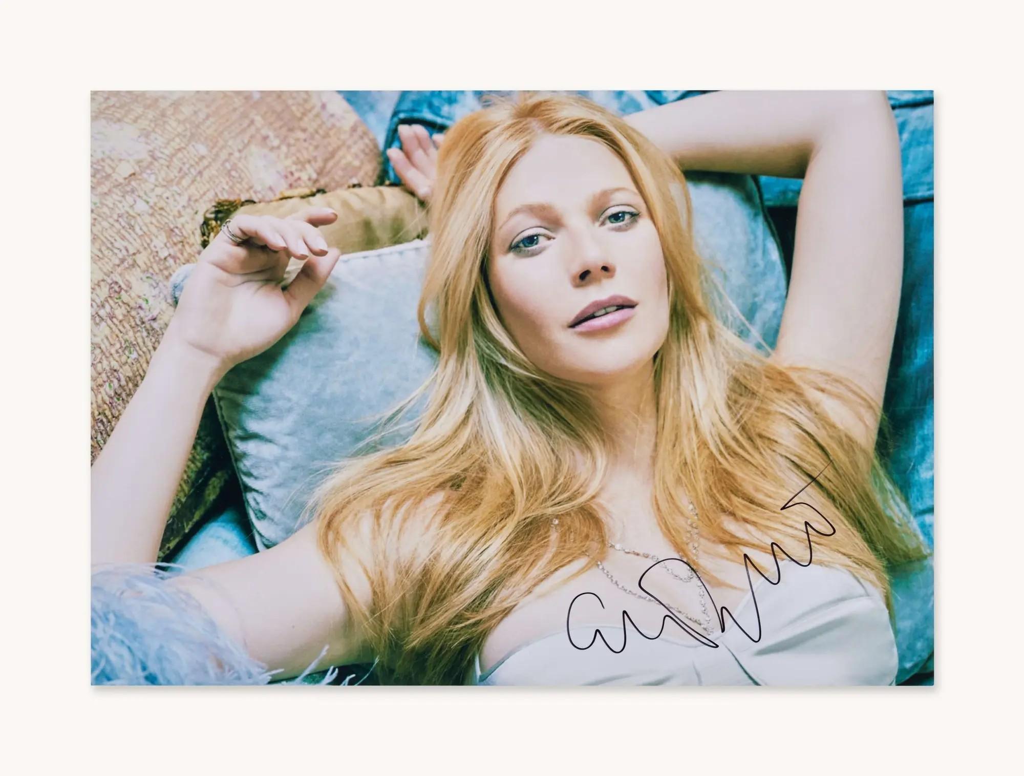 a signed photo of gwyneth paltrow laying on a bed of blue pillows