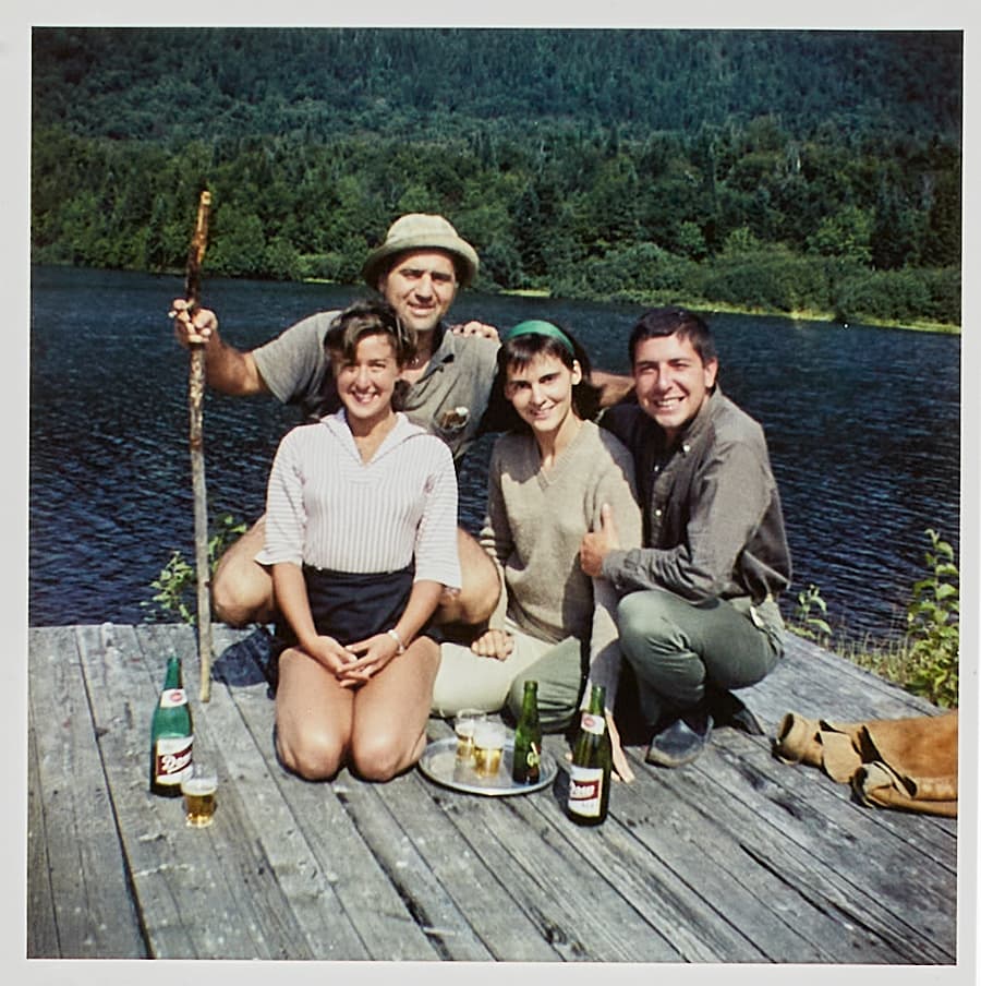 a group of people are posing for a picture on a dock with bottles of beer and a tray of food
