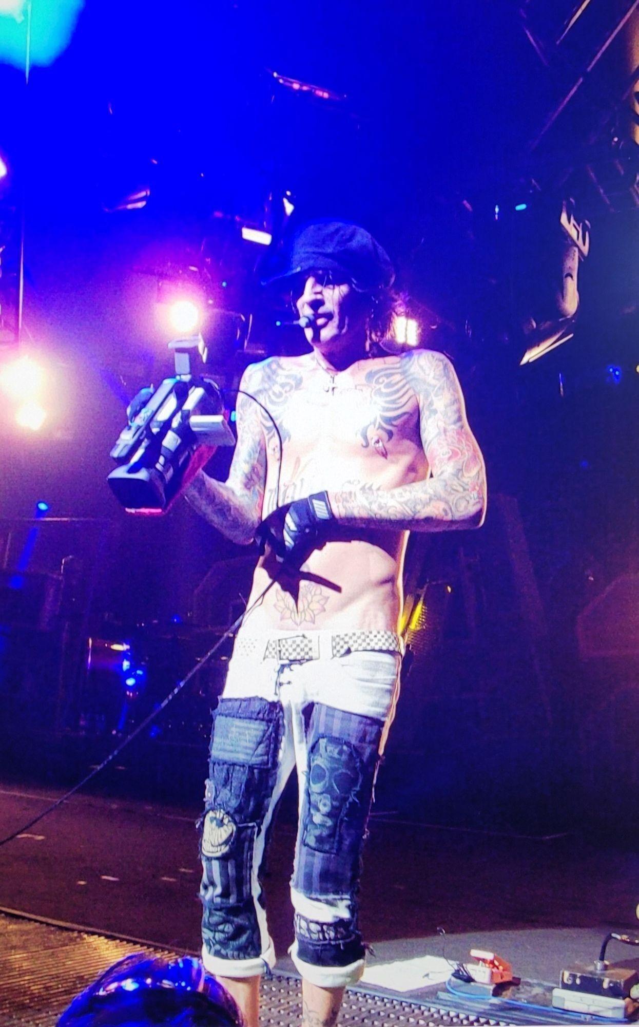 a shirtless man is holding a camera on a stage