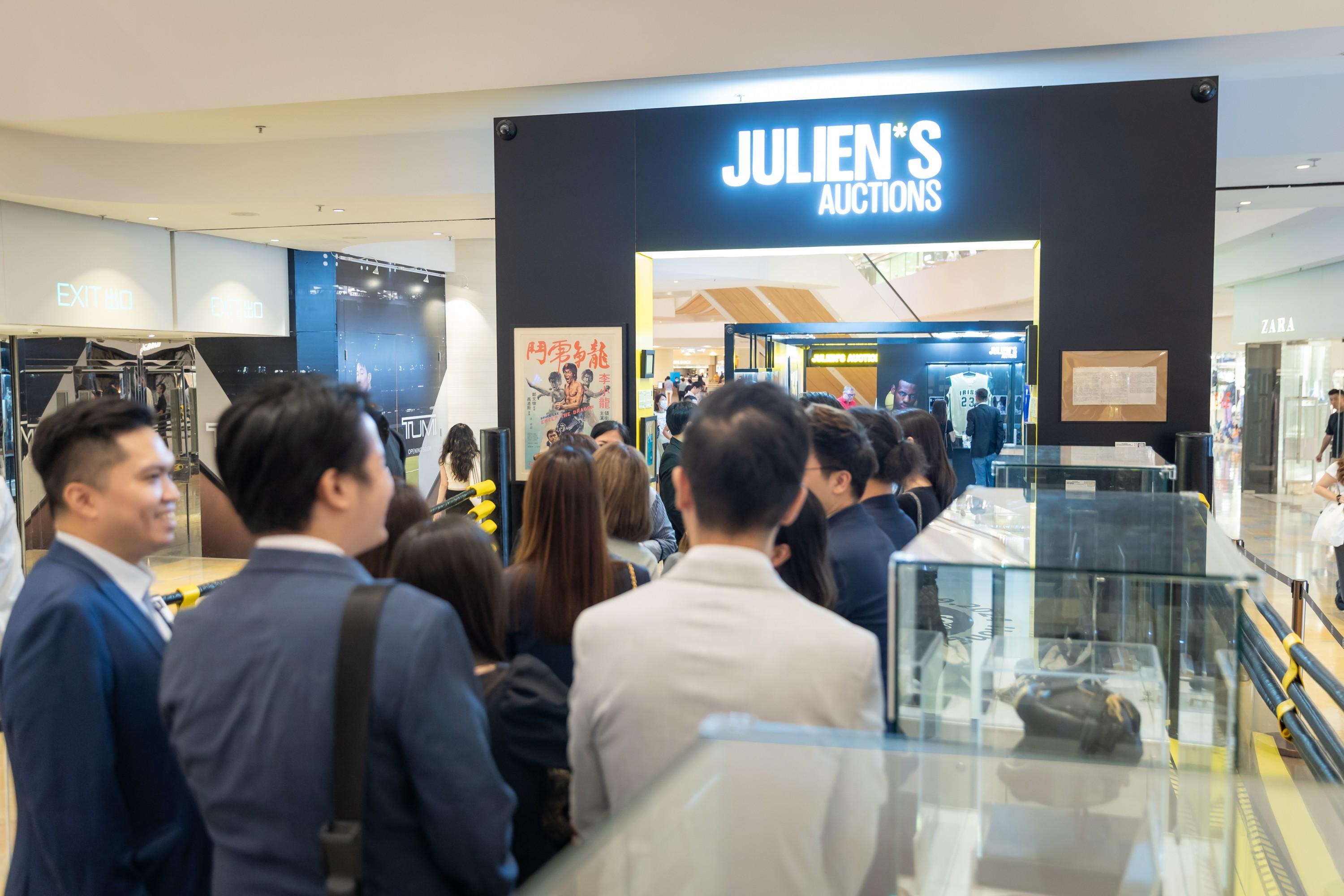 a group of people are standing in front of a store called julien 's auctions .
