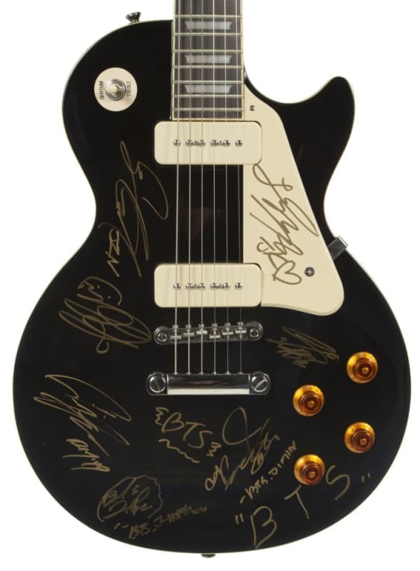 Black electric guitar signed by BTS members in gold ink.