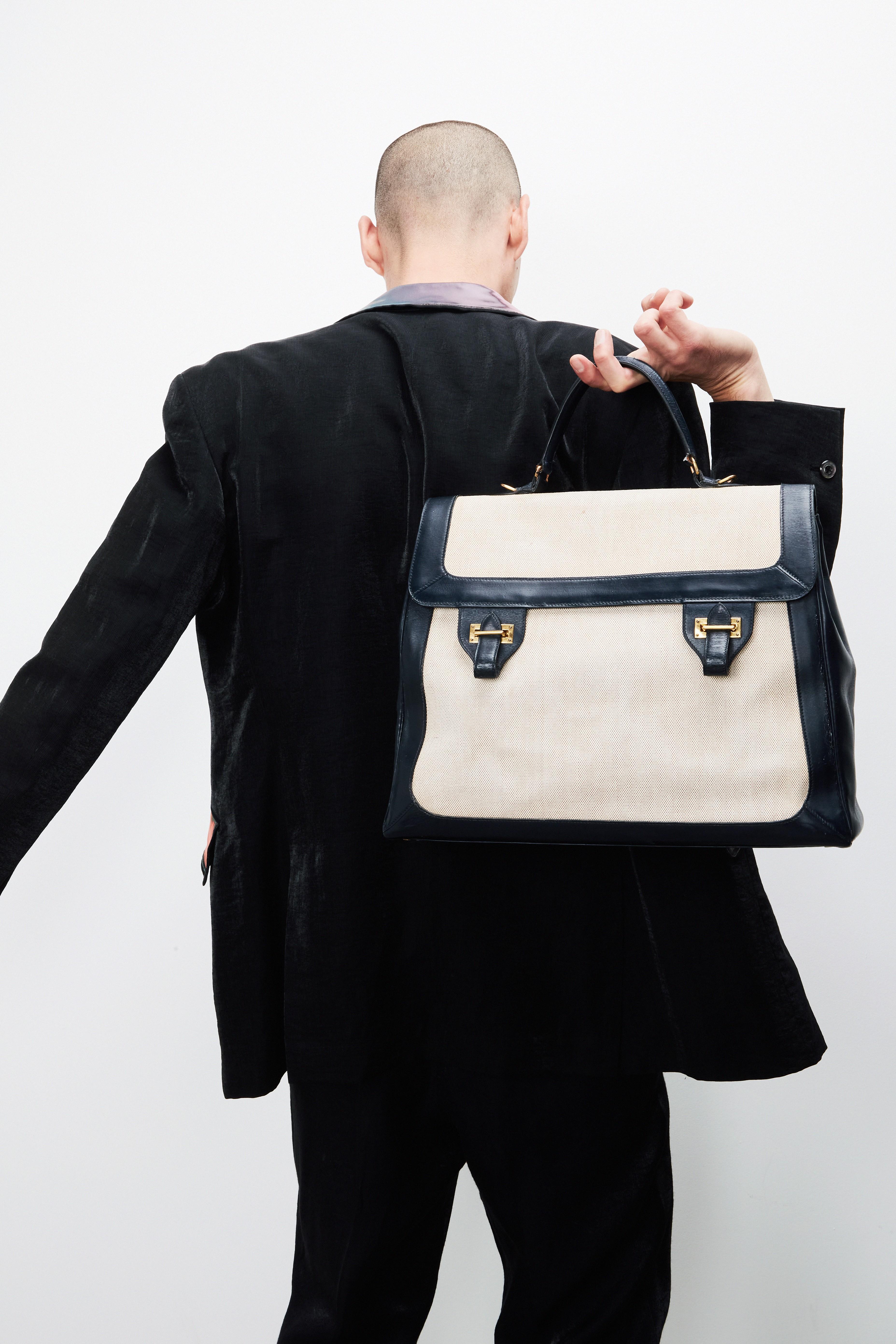 a man holding an hermes bag over his shoulder
