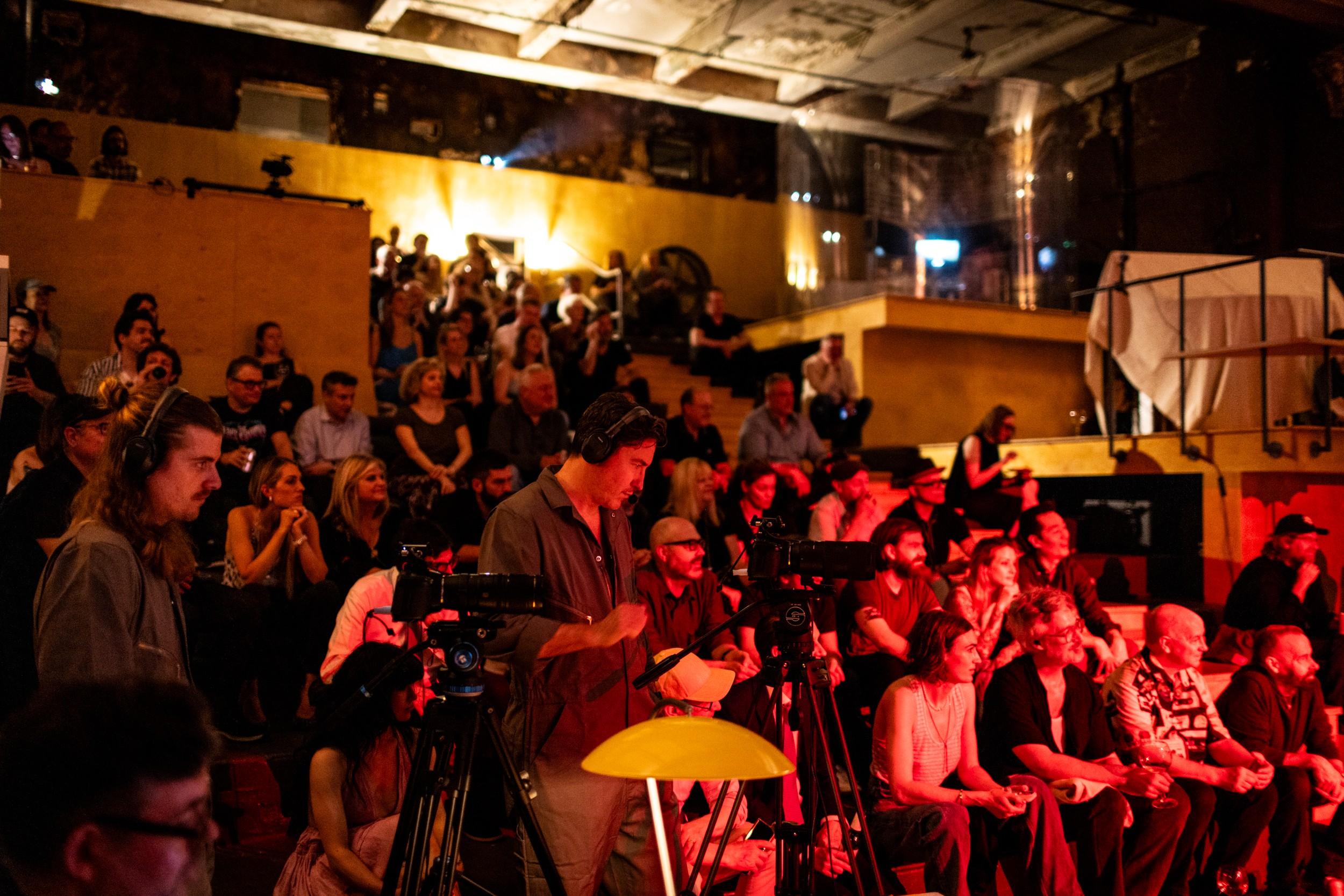 a group of people are sitting in a dark room watching a performance .