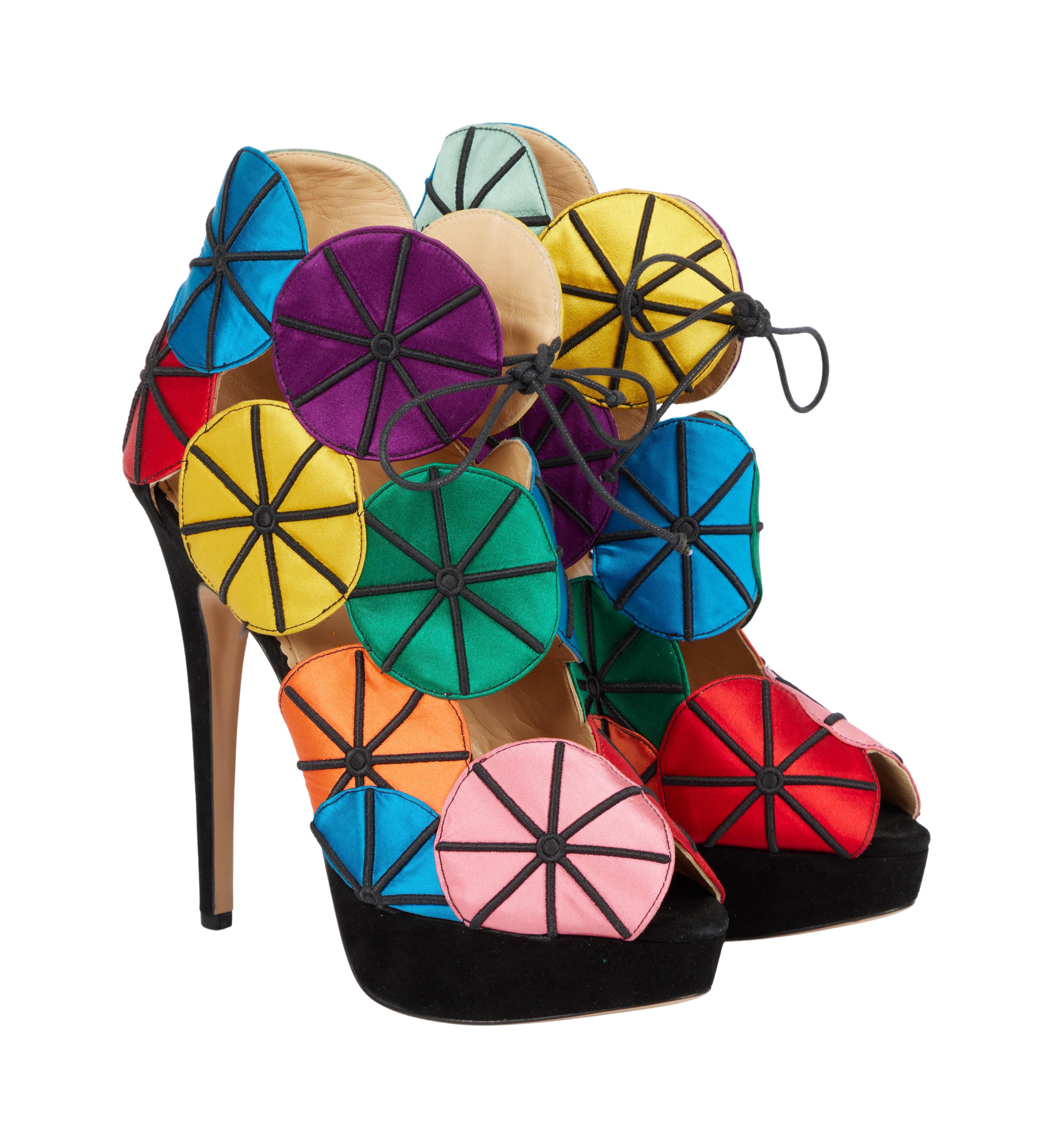 A pair of vibrant, multicolored satin disc-covered high-heeled platform sandals with black stitching and a black base.