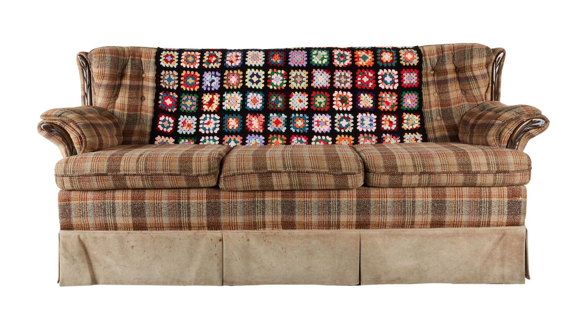 a plaid couch with a multi-colored afghan