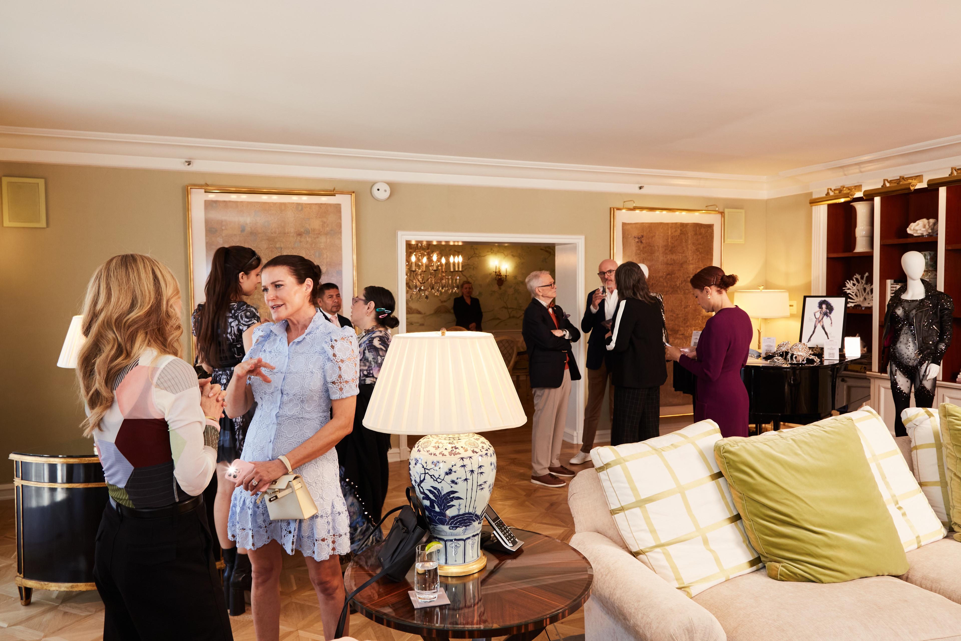 a group of people are standing in a living room talking to each other .