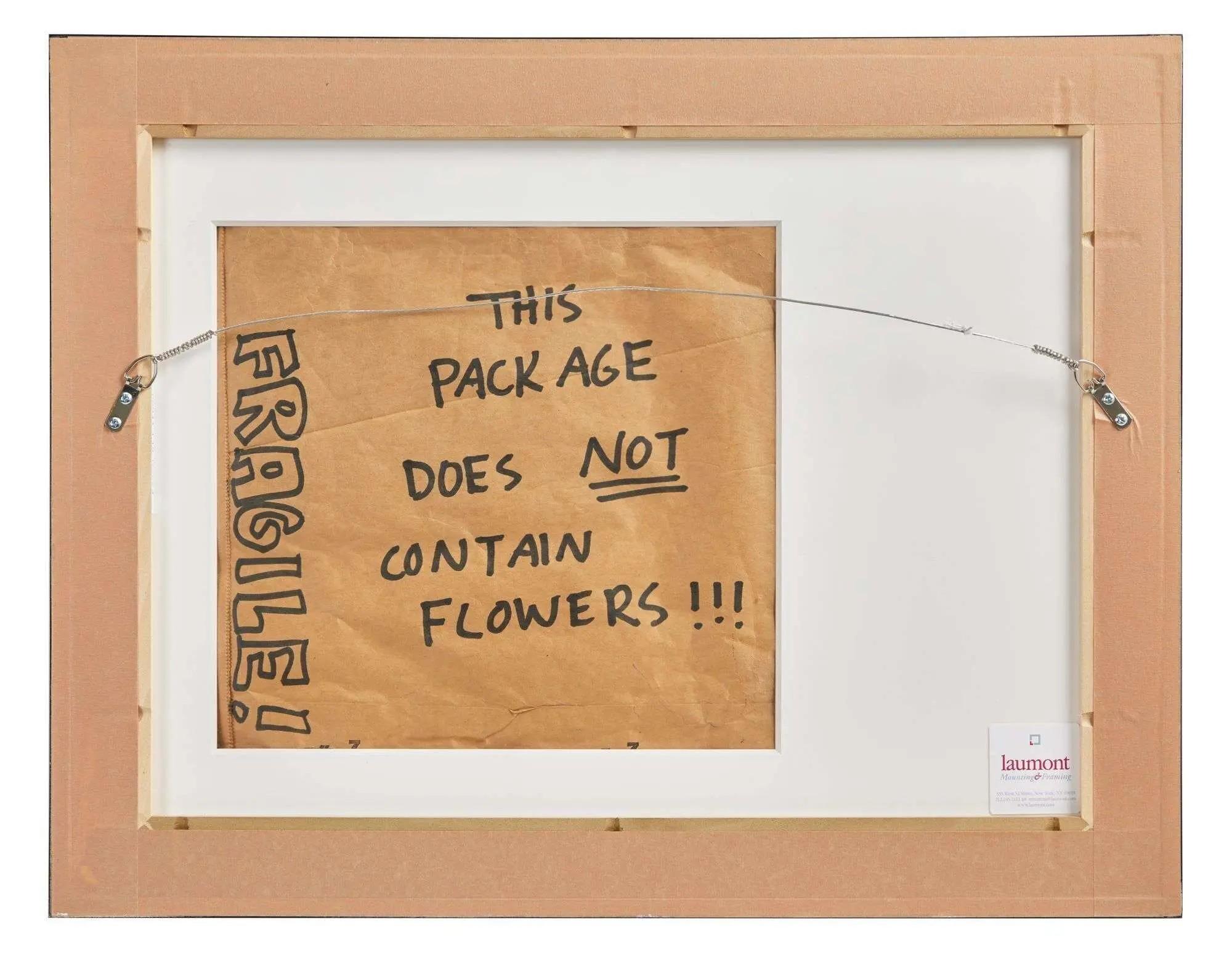 The back of a framed artwork with brown paper reading "THIS PACKAGE DOES NOT CONTAIN FLOWERS!!!" and "FRAGILE!".