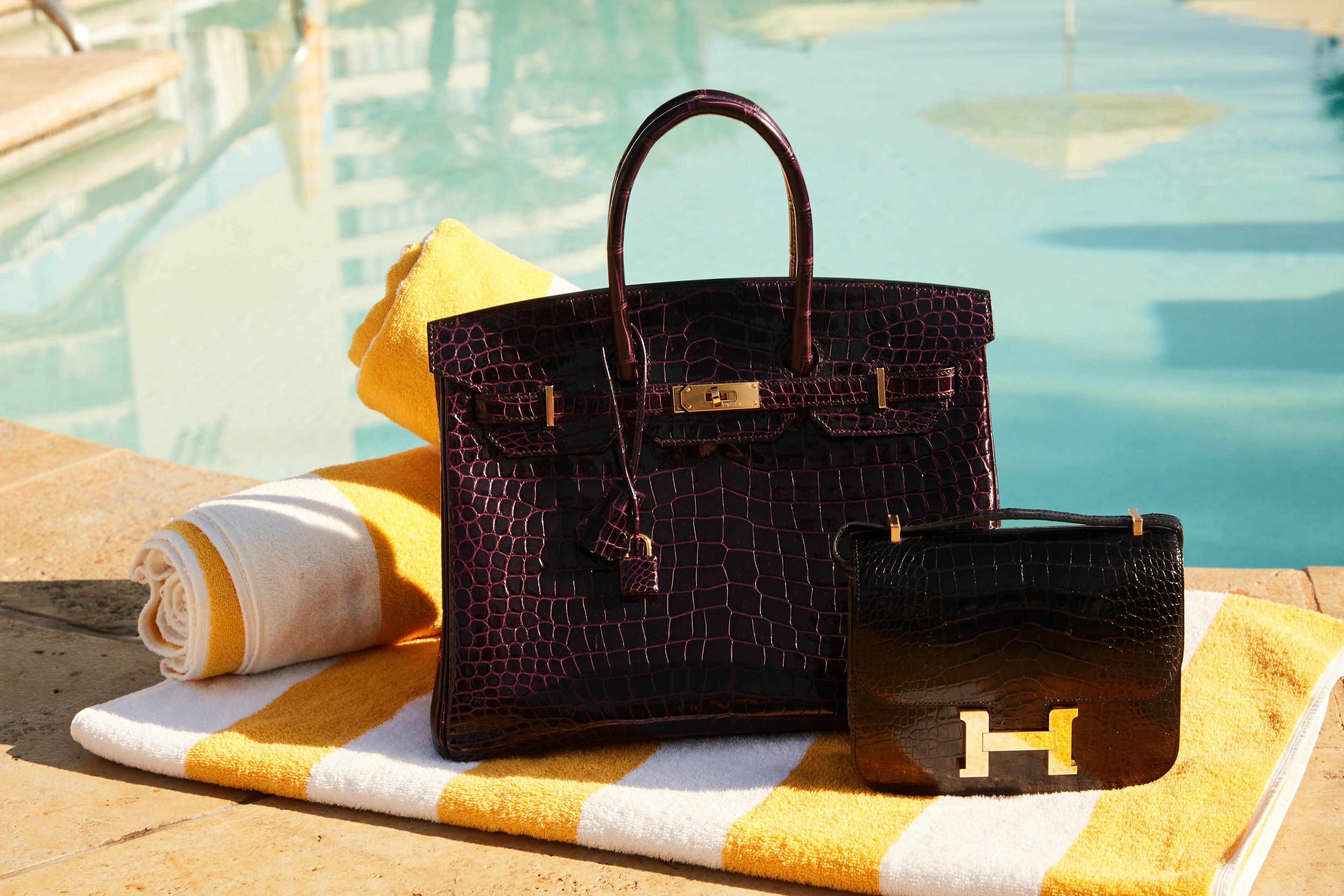 a purse and wallet are sitting on a striped towel next to a pool .