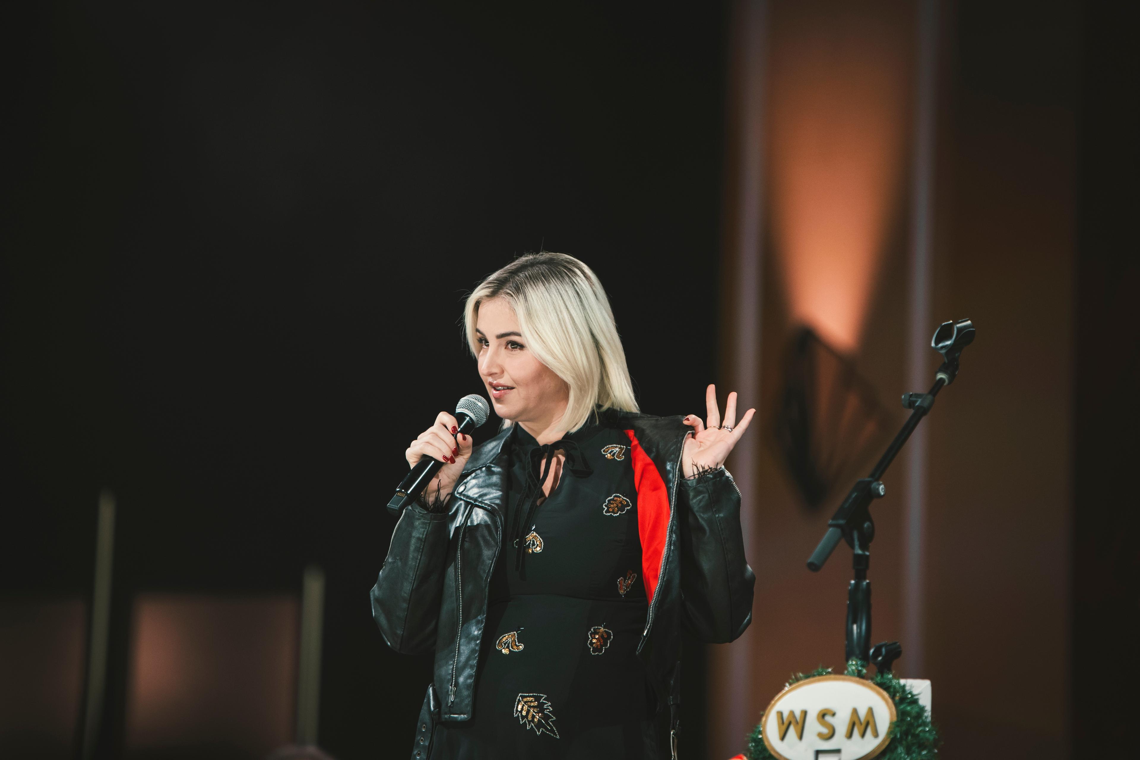 a woman is standing on a stage holding a microphone .
