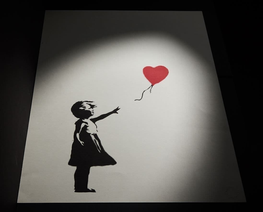 a black and white painting of a girl holding a red heart shaped balloon .