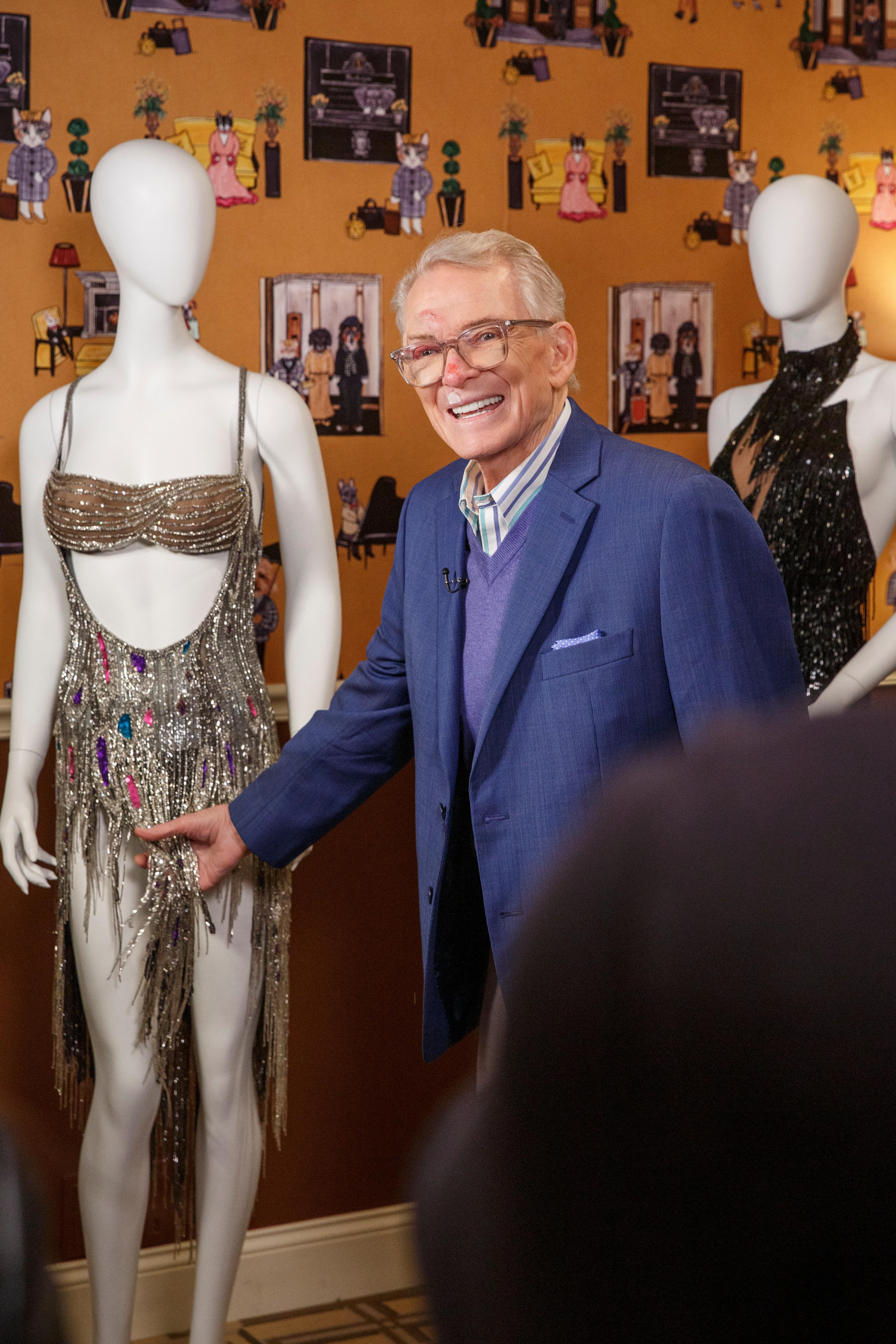 a man in a suit stands next to a mannequin wearing a dress