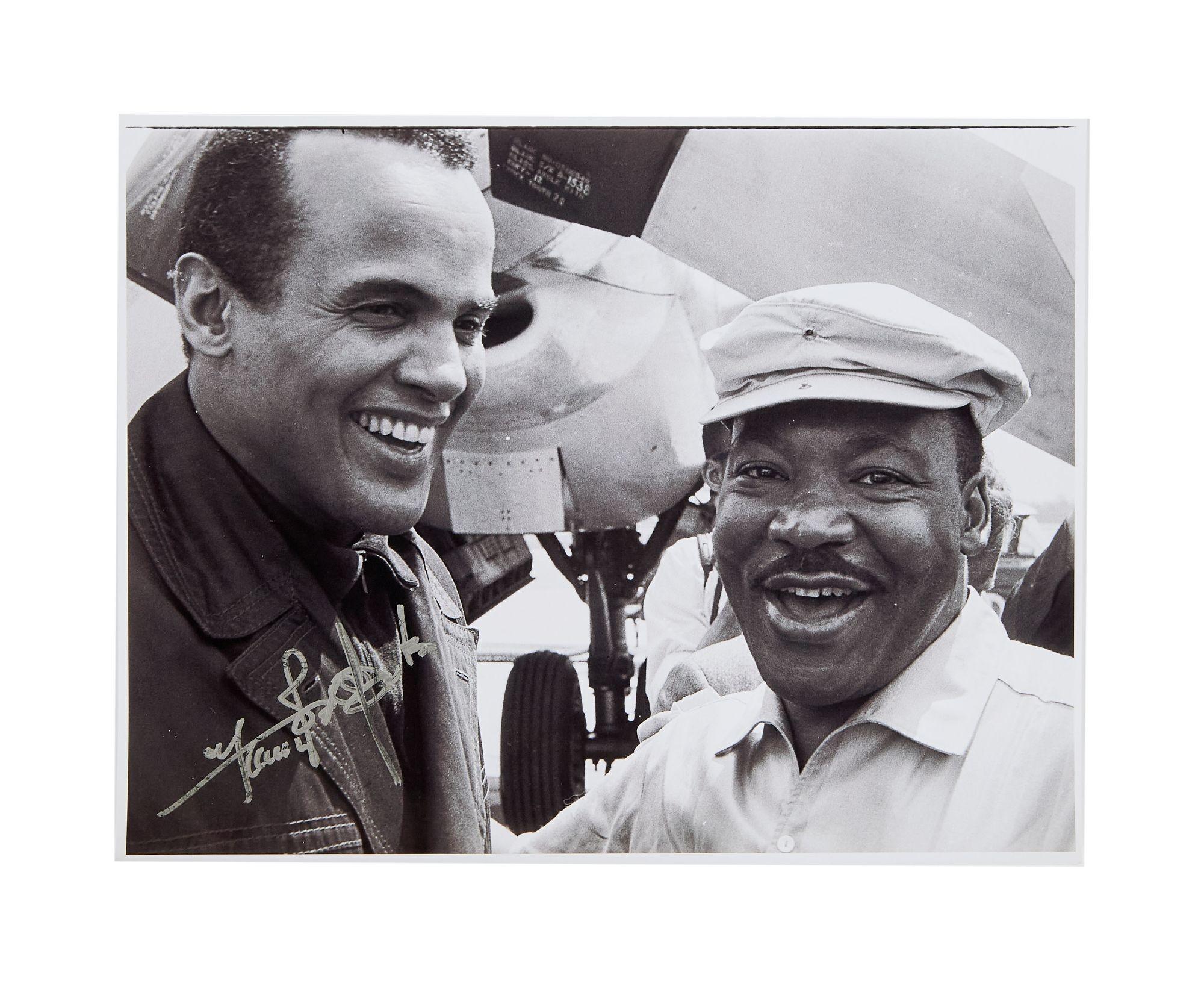 Lot #52. Harry Belafonte | Signed Photo with Dr. Martin Luther King, Jr. a black and white photo of two men smiling in front of an airplane .