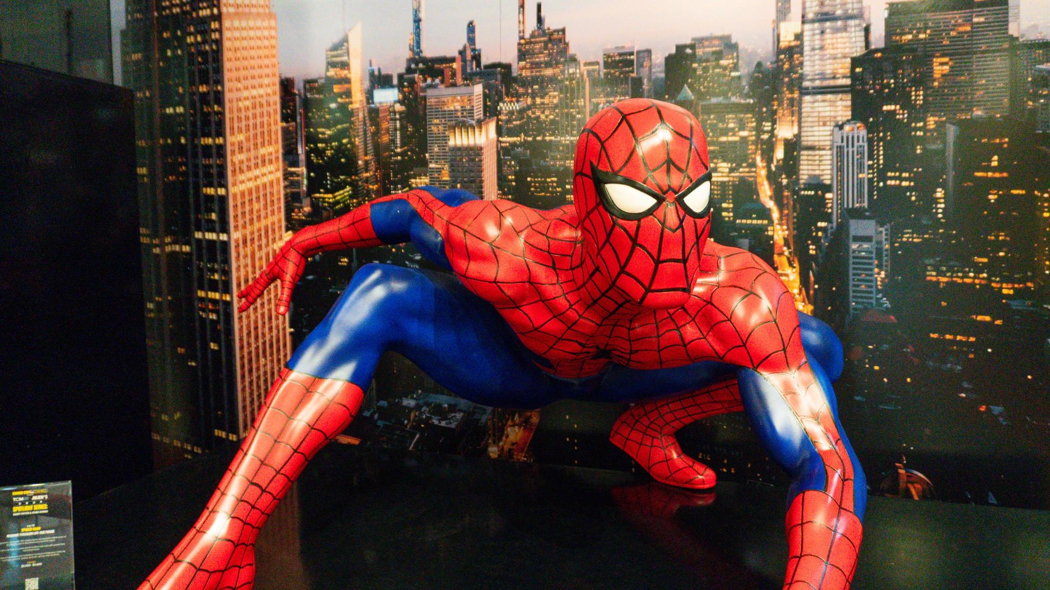a statue of spider-man is standing in front of a city skyline .