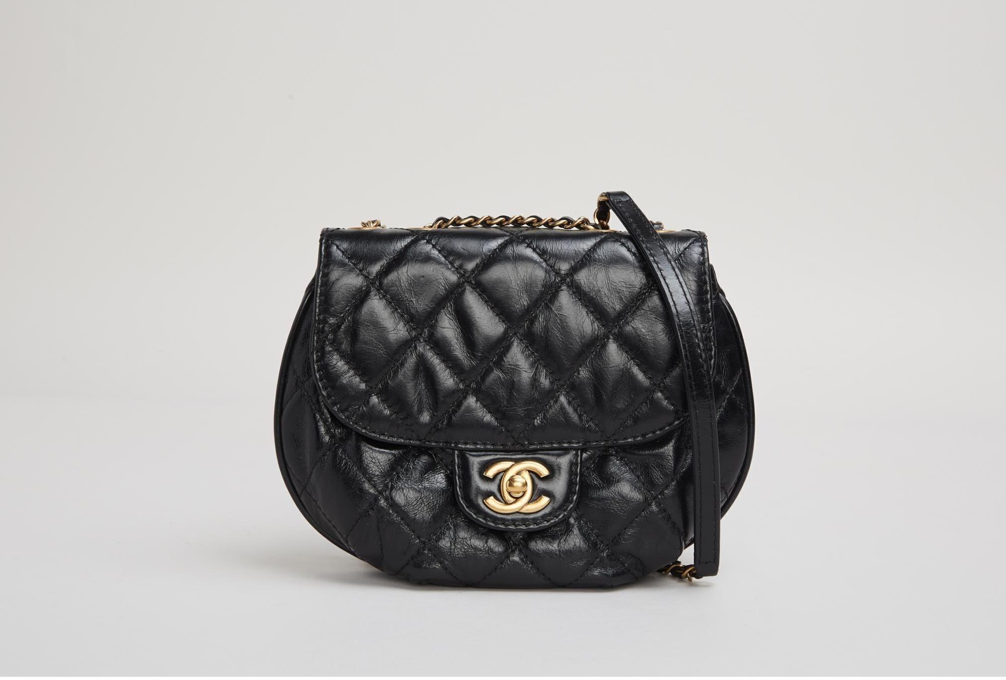 a black chanel purse with a gold chain on a white background .