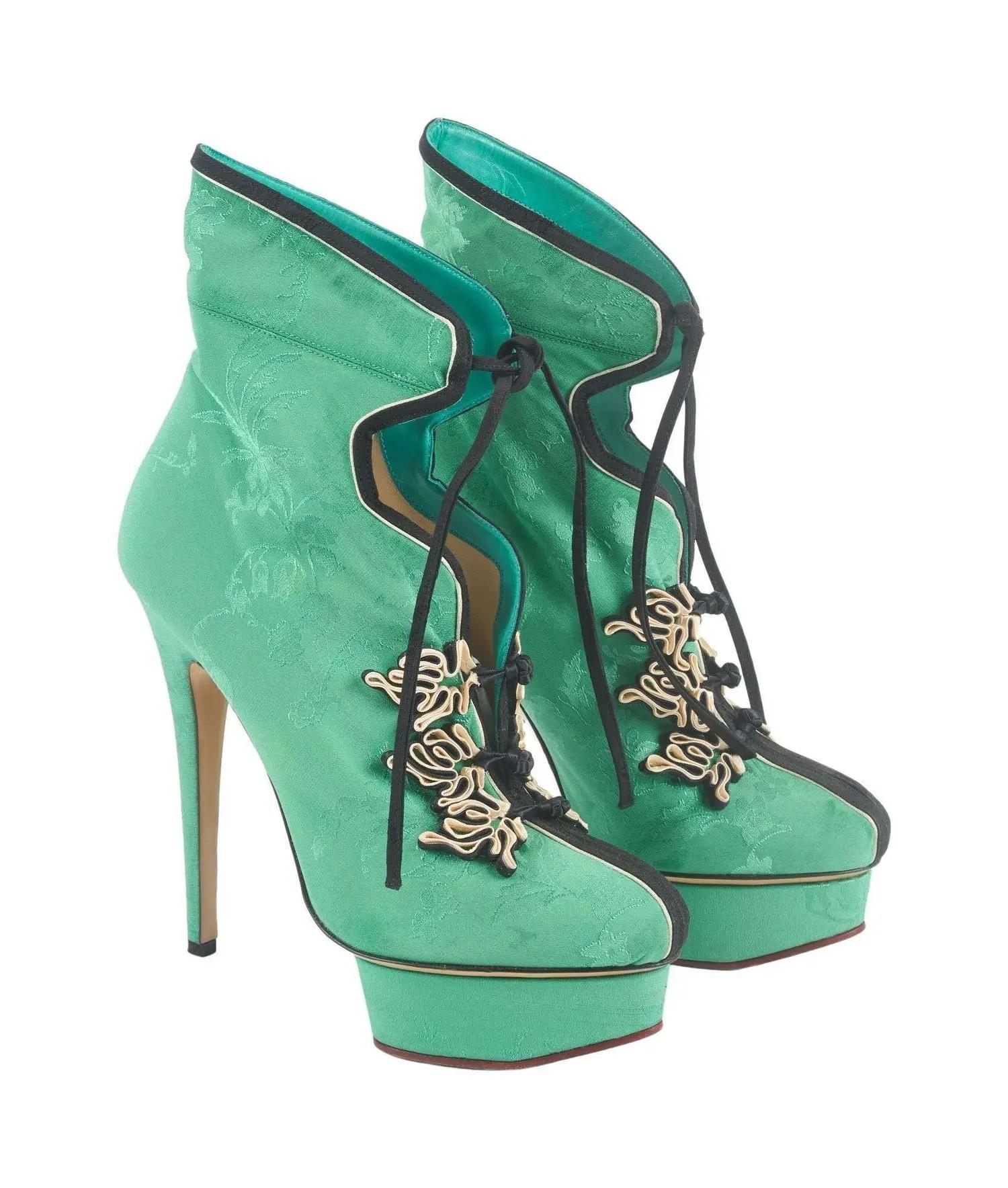 A pair of mint green brocade ankle boots with high heels, platform soles, black trim, and gold frog closures.