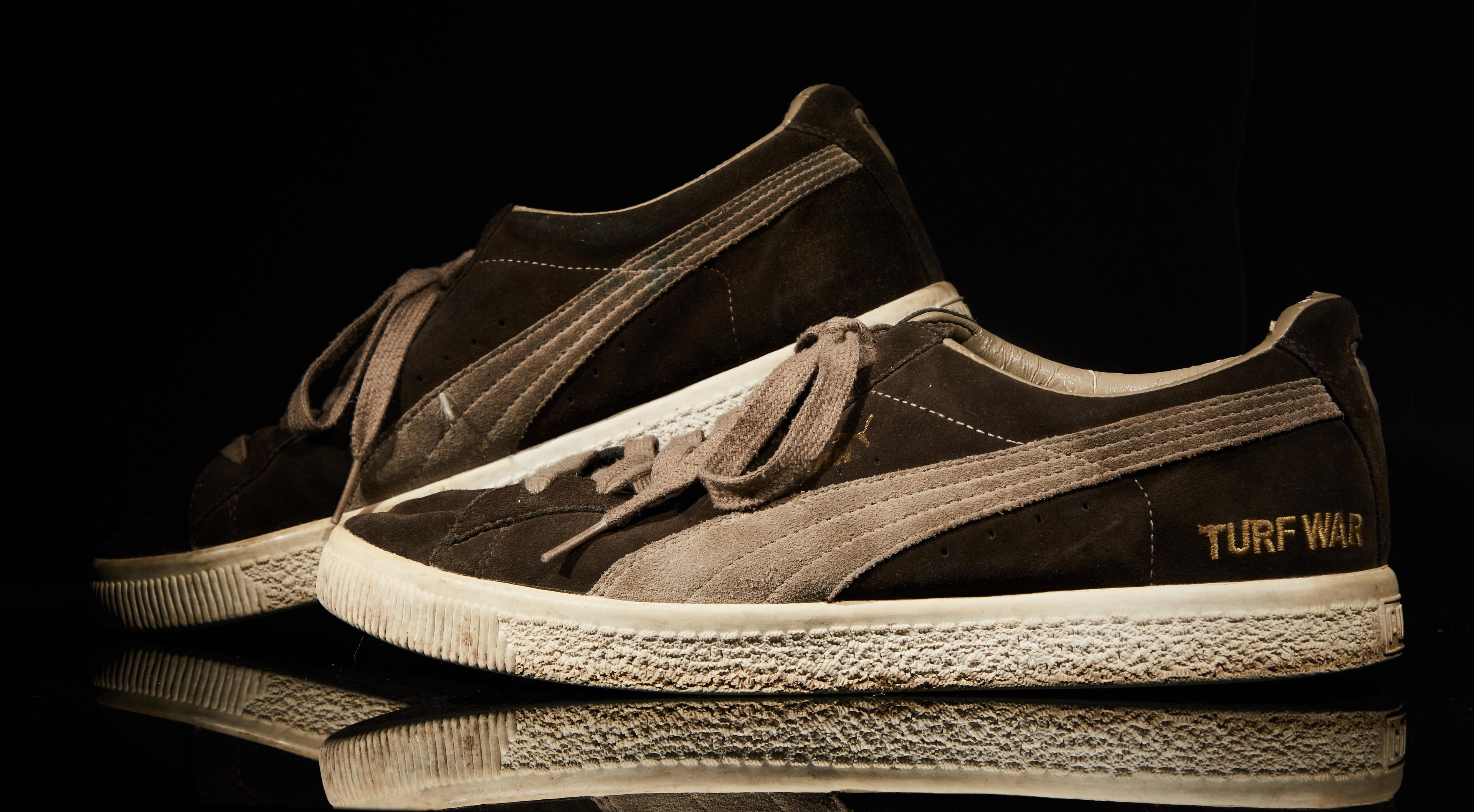 a pair of brown and white puma sneakers on a black surface .