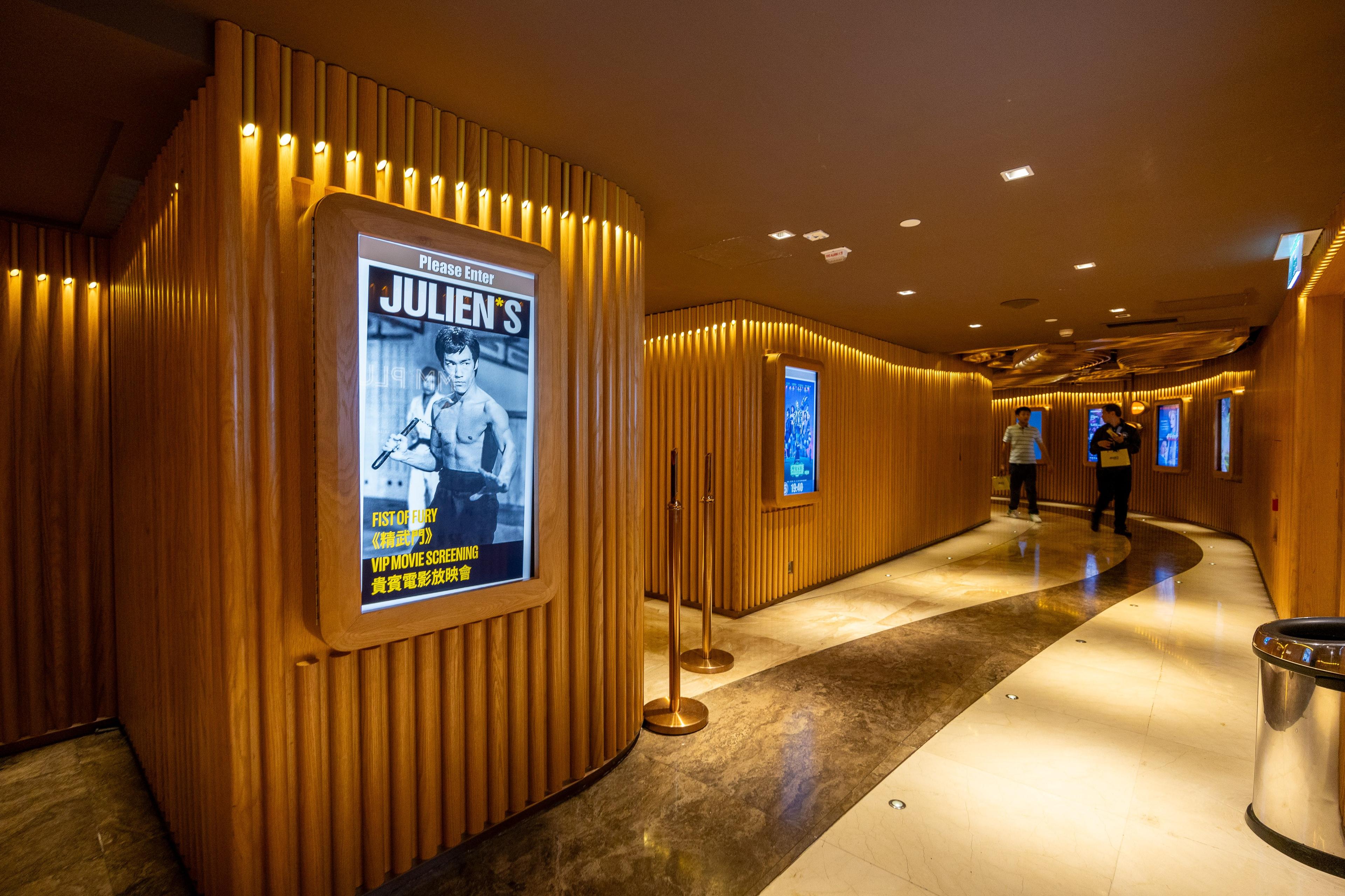 a hallway in a movie theater with a poster of bruce lee on the wall .