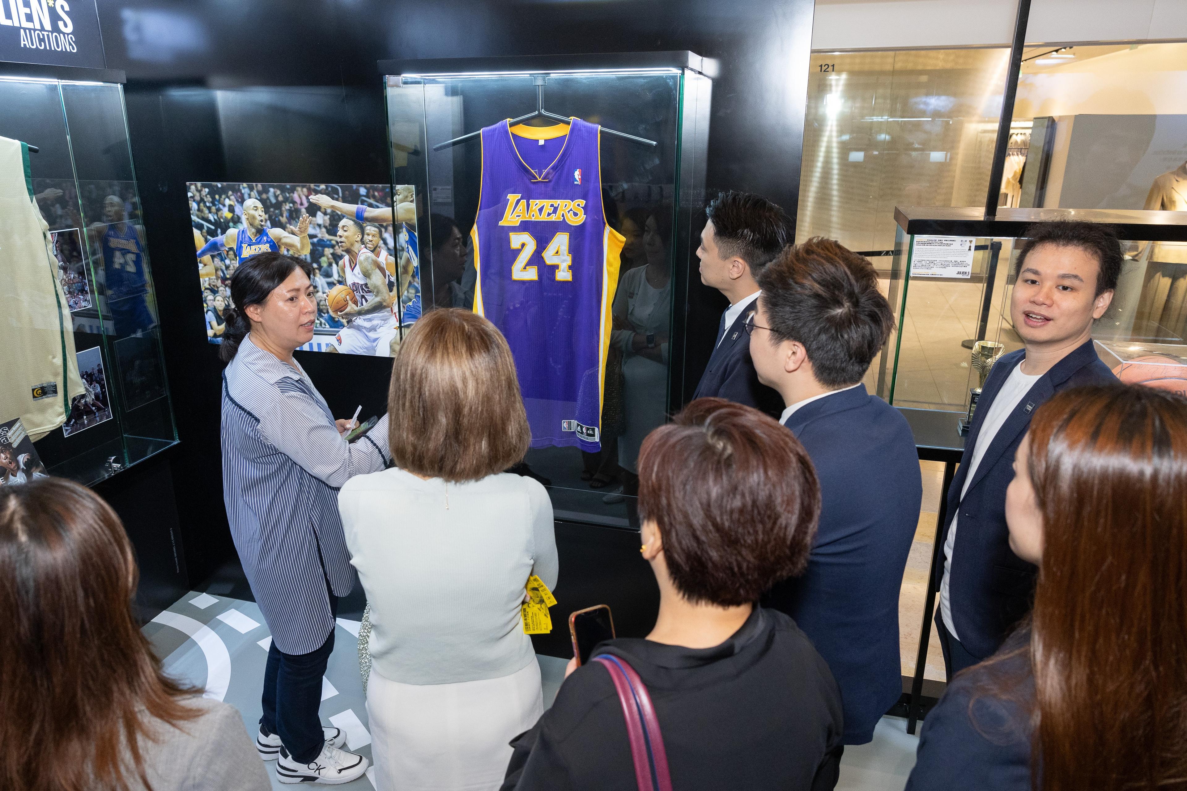 a group of people are looking at a basketball jersey hanging on a wall .