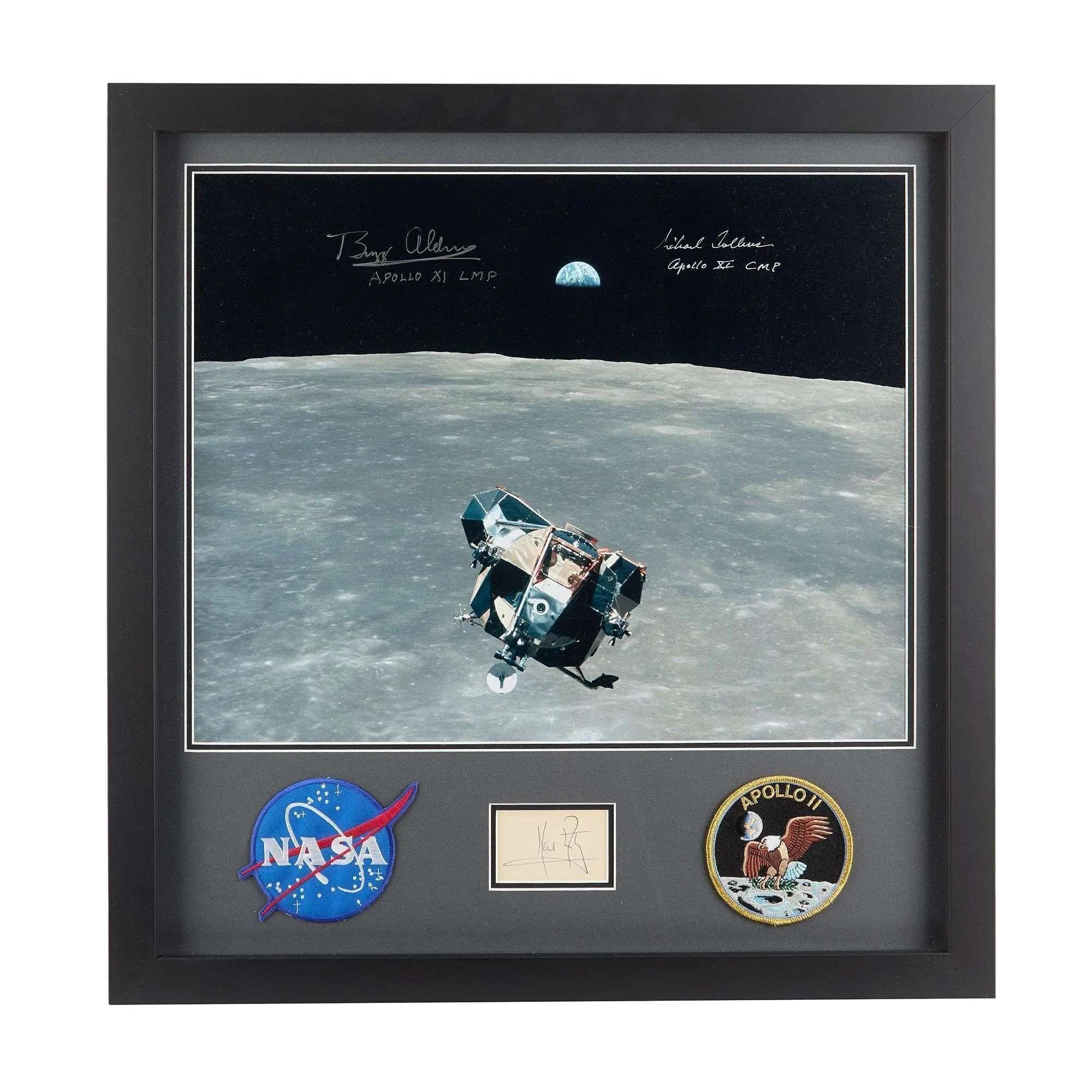 A framed Apollo 11 display with a signed photo of the Lunar Module over the Moon with Earth, a NASA patch, an Apollo 11 mission patch, and Neil Armstrong's autograph.