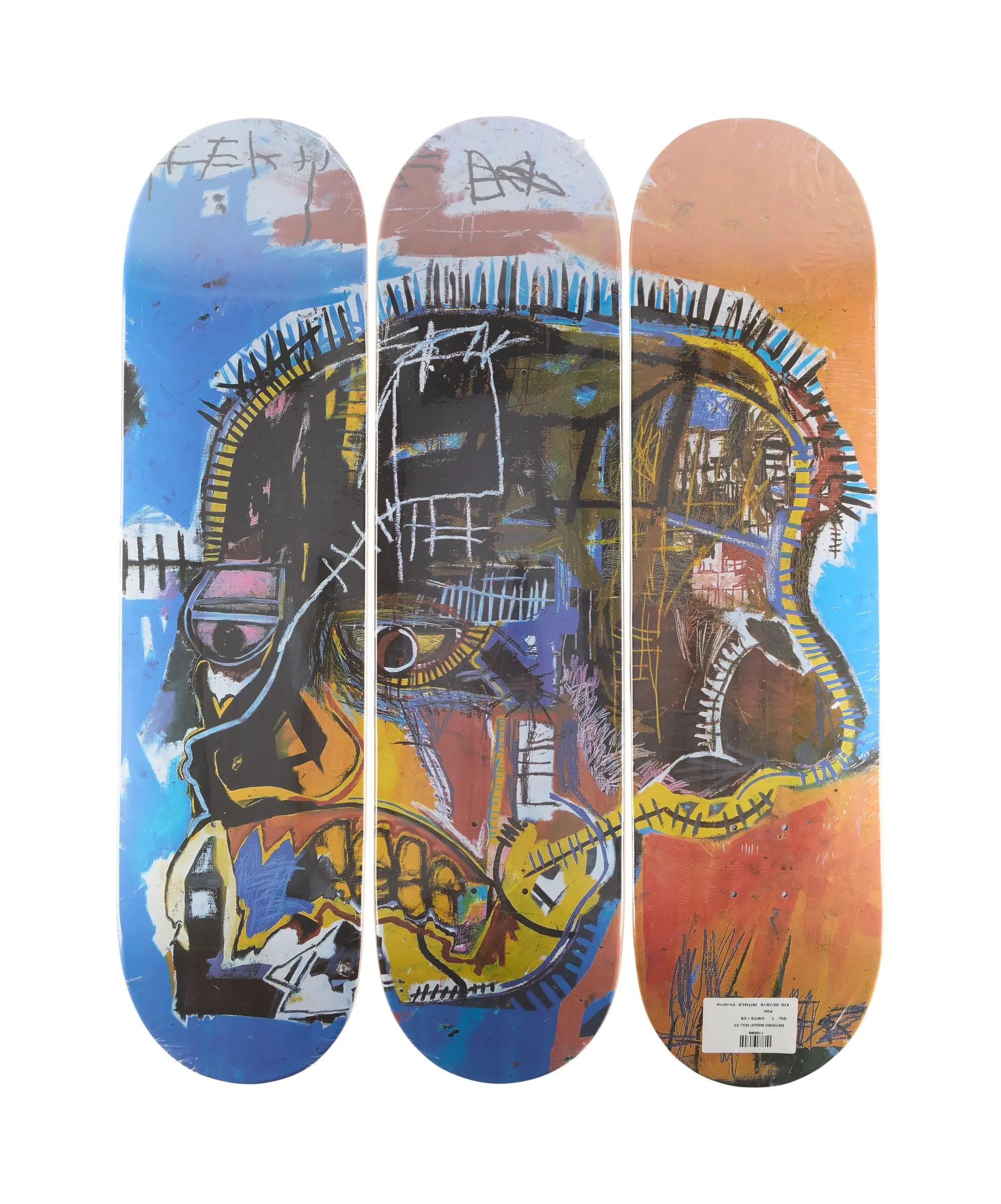 Lot #29. Jean-Michel Basquiat | "Skull" Triptych Skateboard Decks (3) Three skateboard decks side-by-side displaying a colorful, abstract Jean-Michel Basquiat "Skull" artwork.