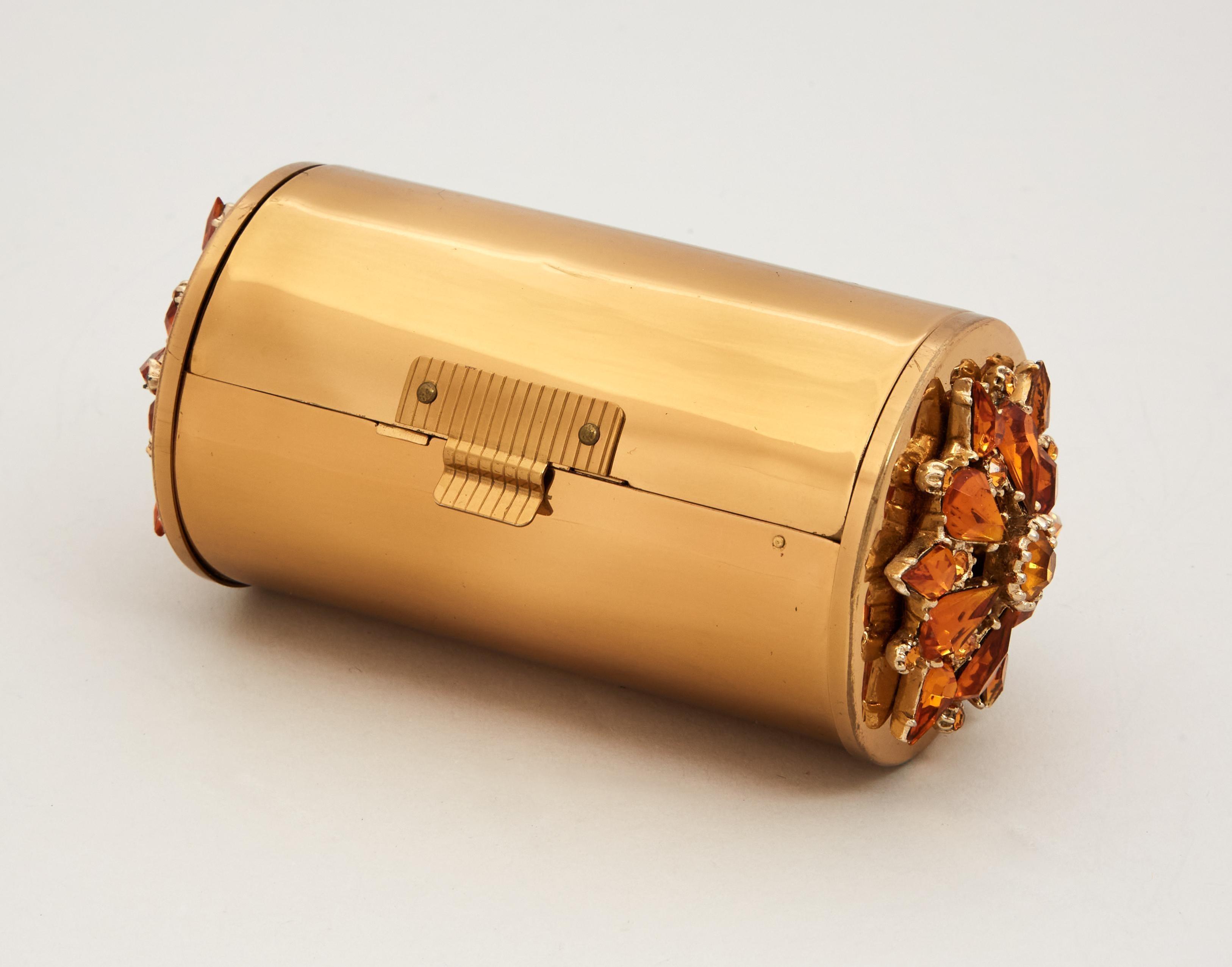 a close up of a gold cylinder with rhinestones on a white surface .