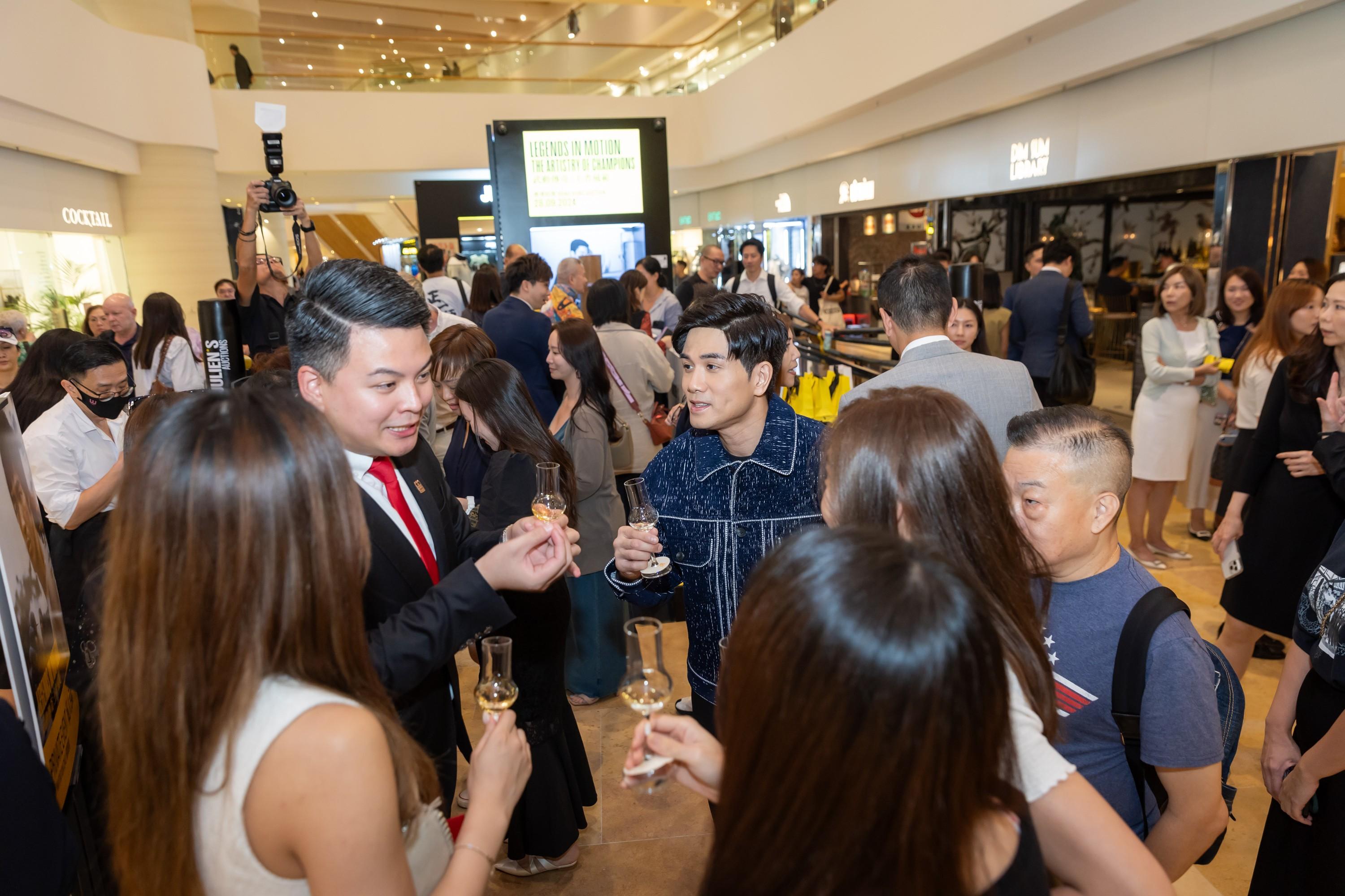 a group of people are standing around a man holding a glass of wine .