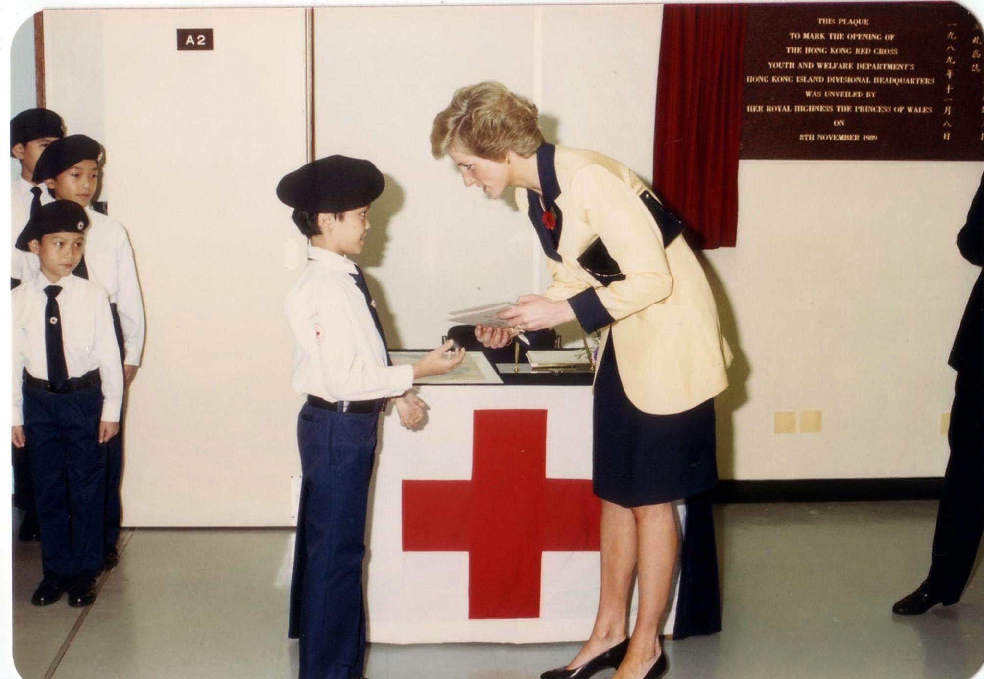 a woman is standing in front of a red cross and talking to a boy .