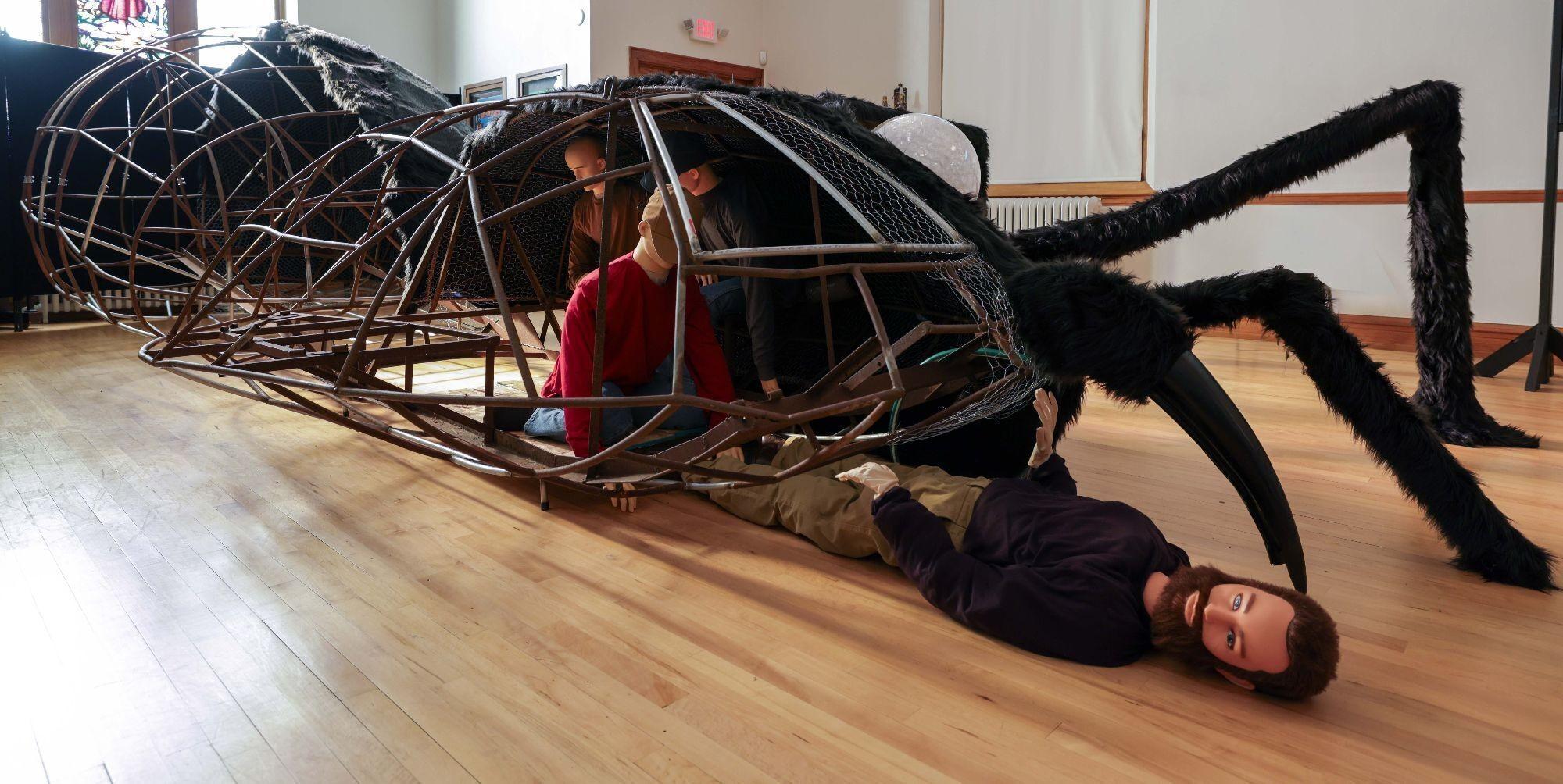 a man is laying on the floor next to a giant spider .