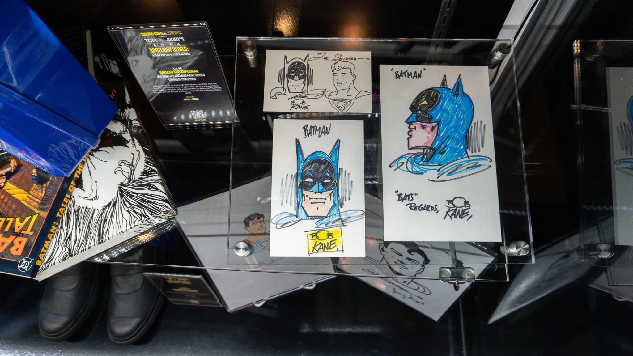 a display case filled with drawings of batman and superman .