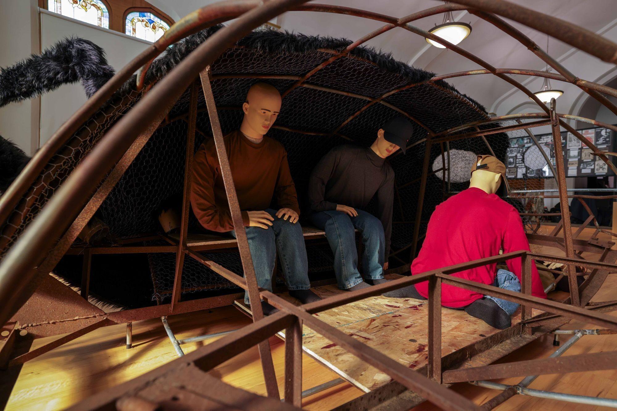 a group of mannequins are sitting inside of a metal structure .