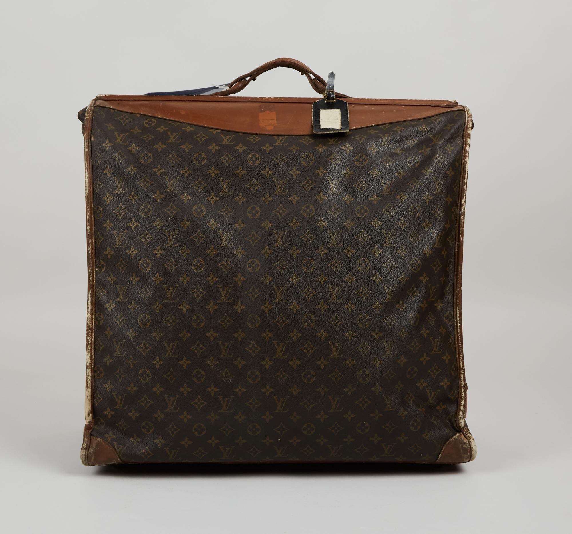 Lot #56. Elizabeth Taylor | The French Company Louis Vuitton Monogram Luggage a large louis vuitton suitcase with a tag attached to it