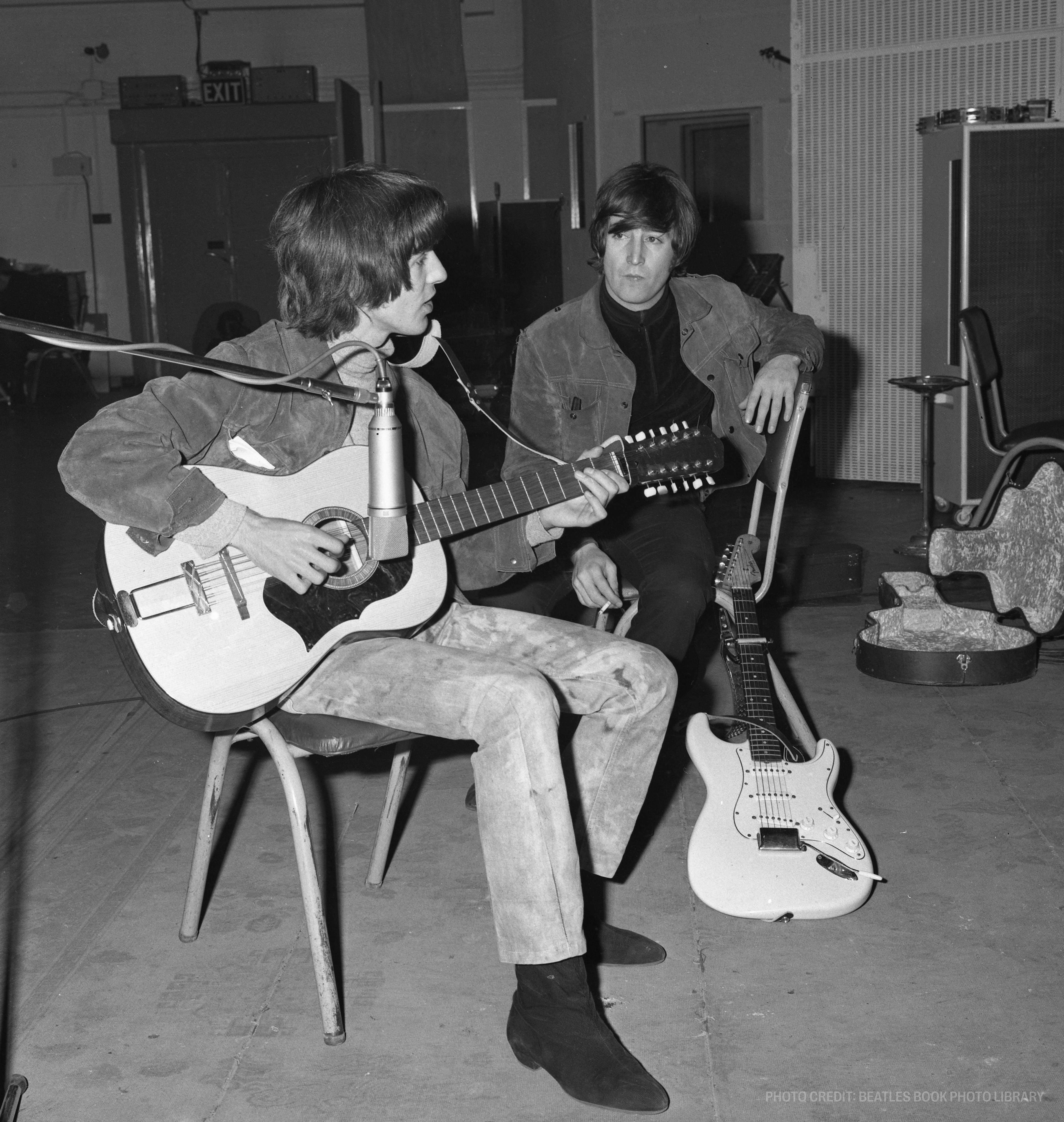 two men playing guitars in front of a sign that says exit