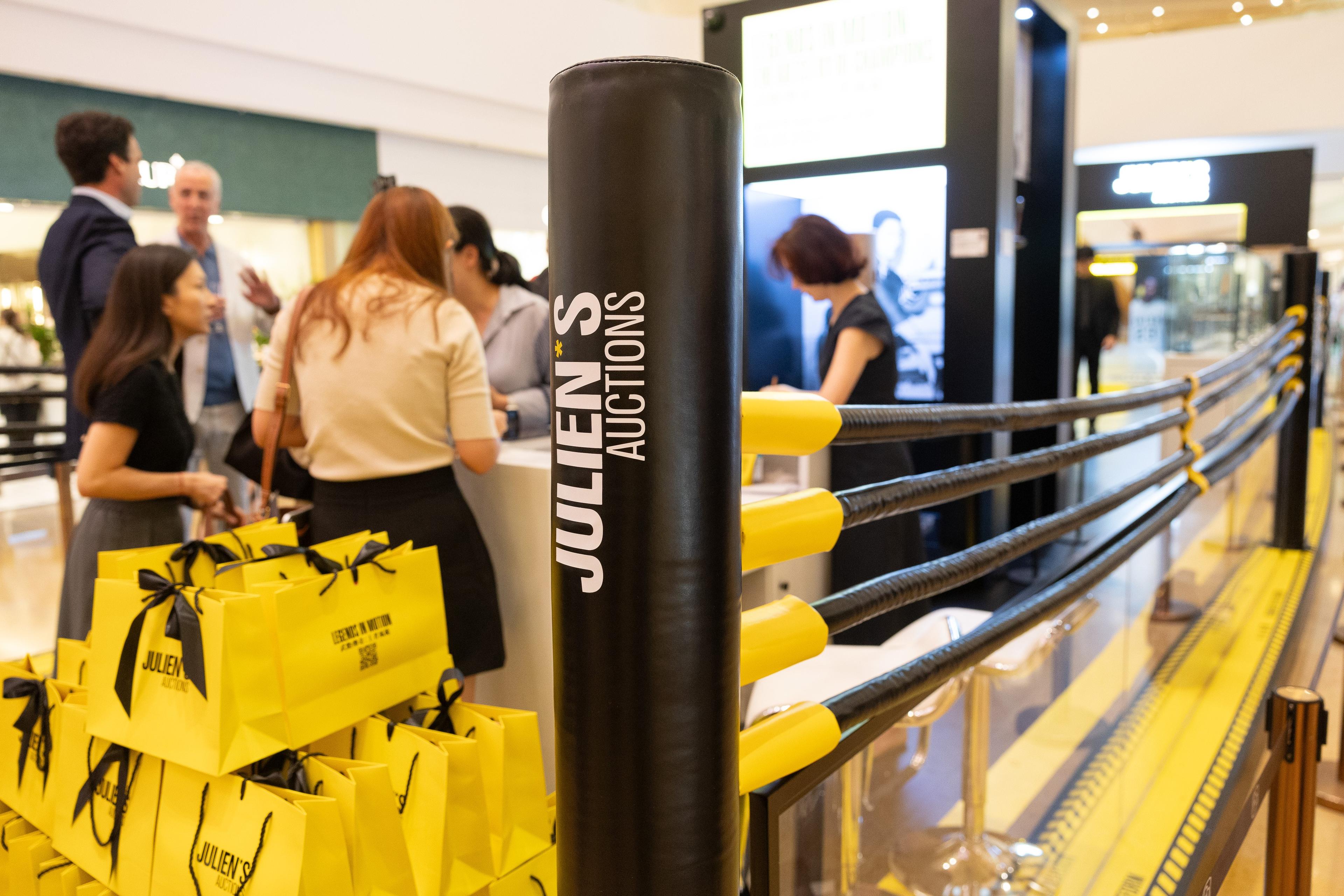 a group of people are standing around a boxing ring in a shopping mall .