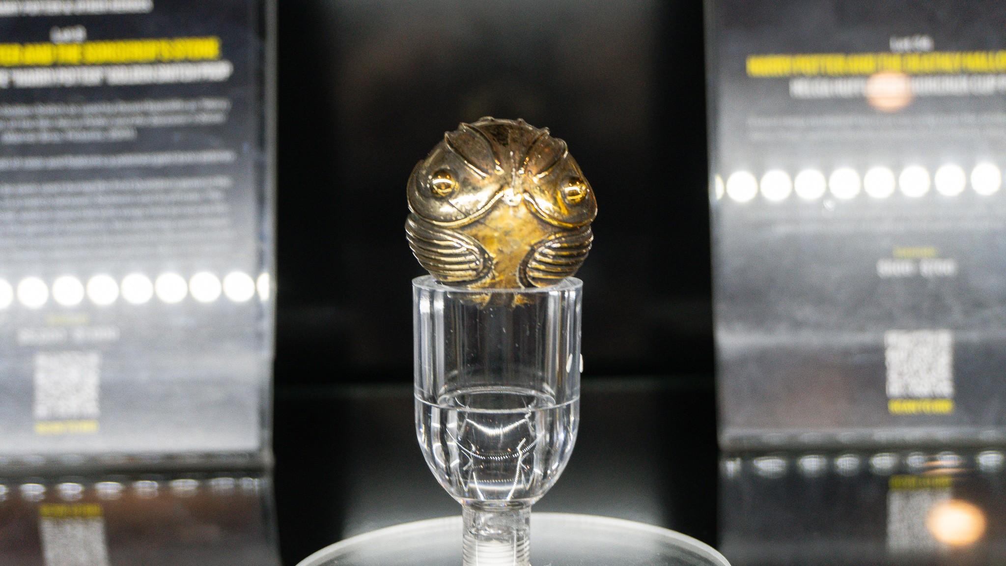 a golden snitch is sitting on top of a glass on a table .