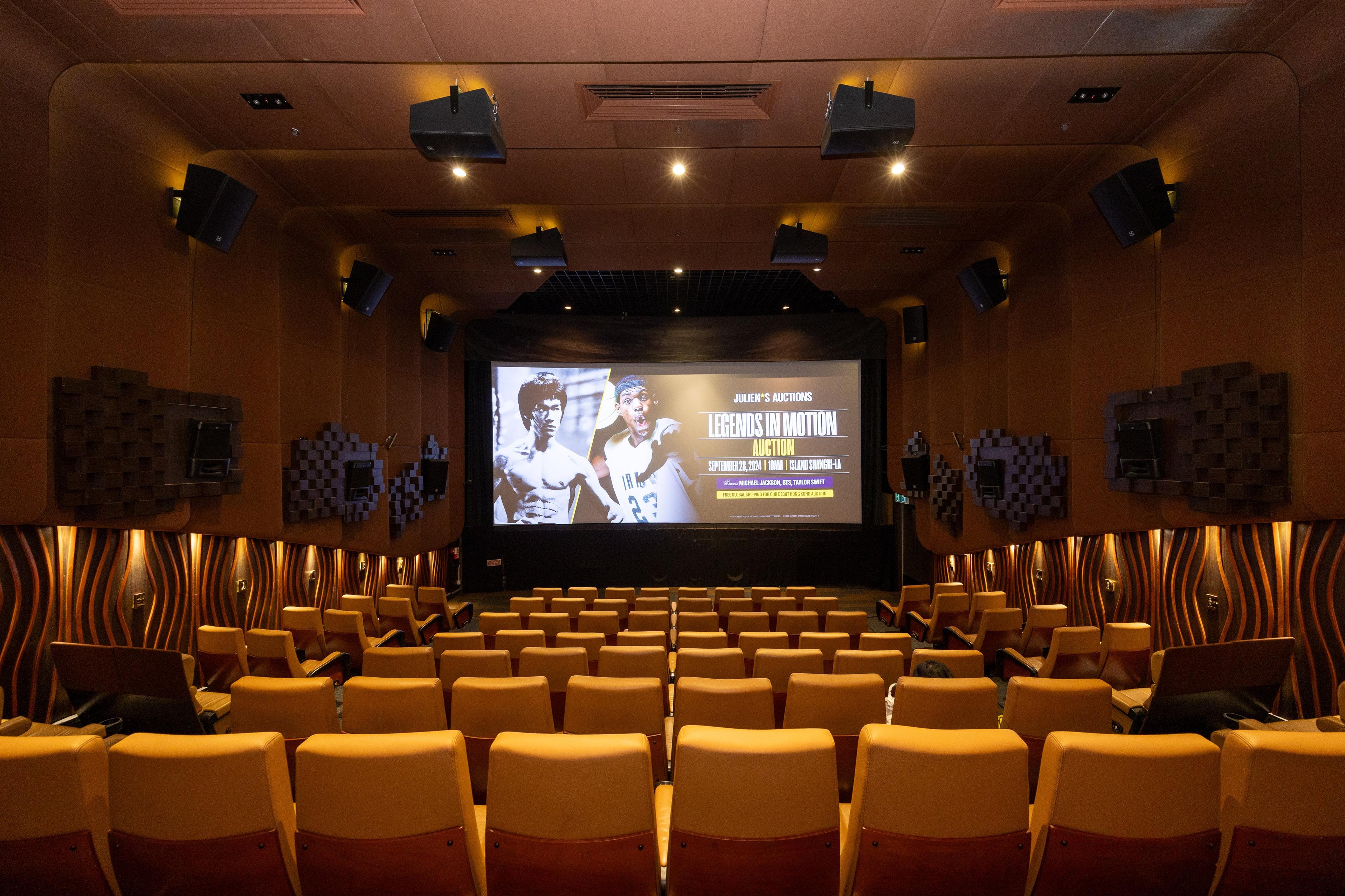 an empty movie theater with rows of seats and a large screen .
