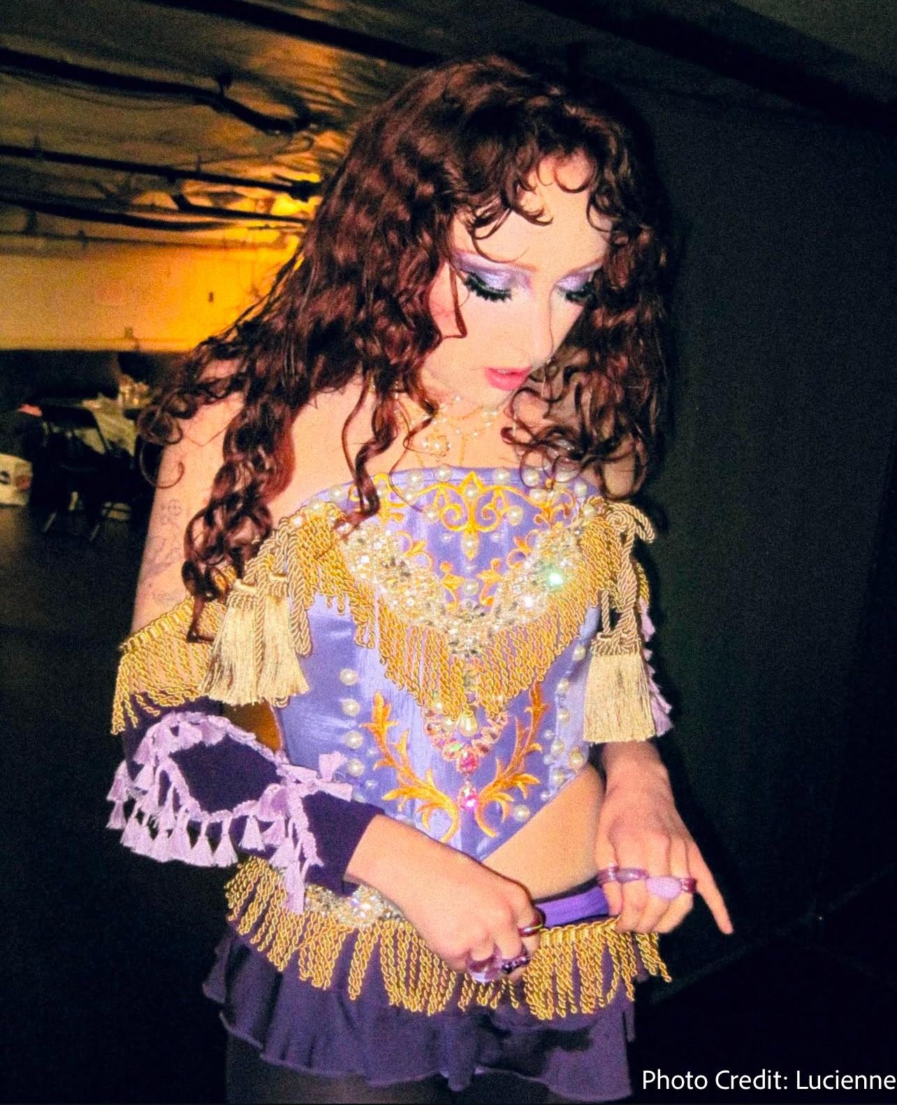 a woman in a purple and gold outfit with the photo credit lucienne