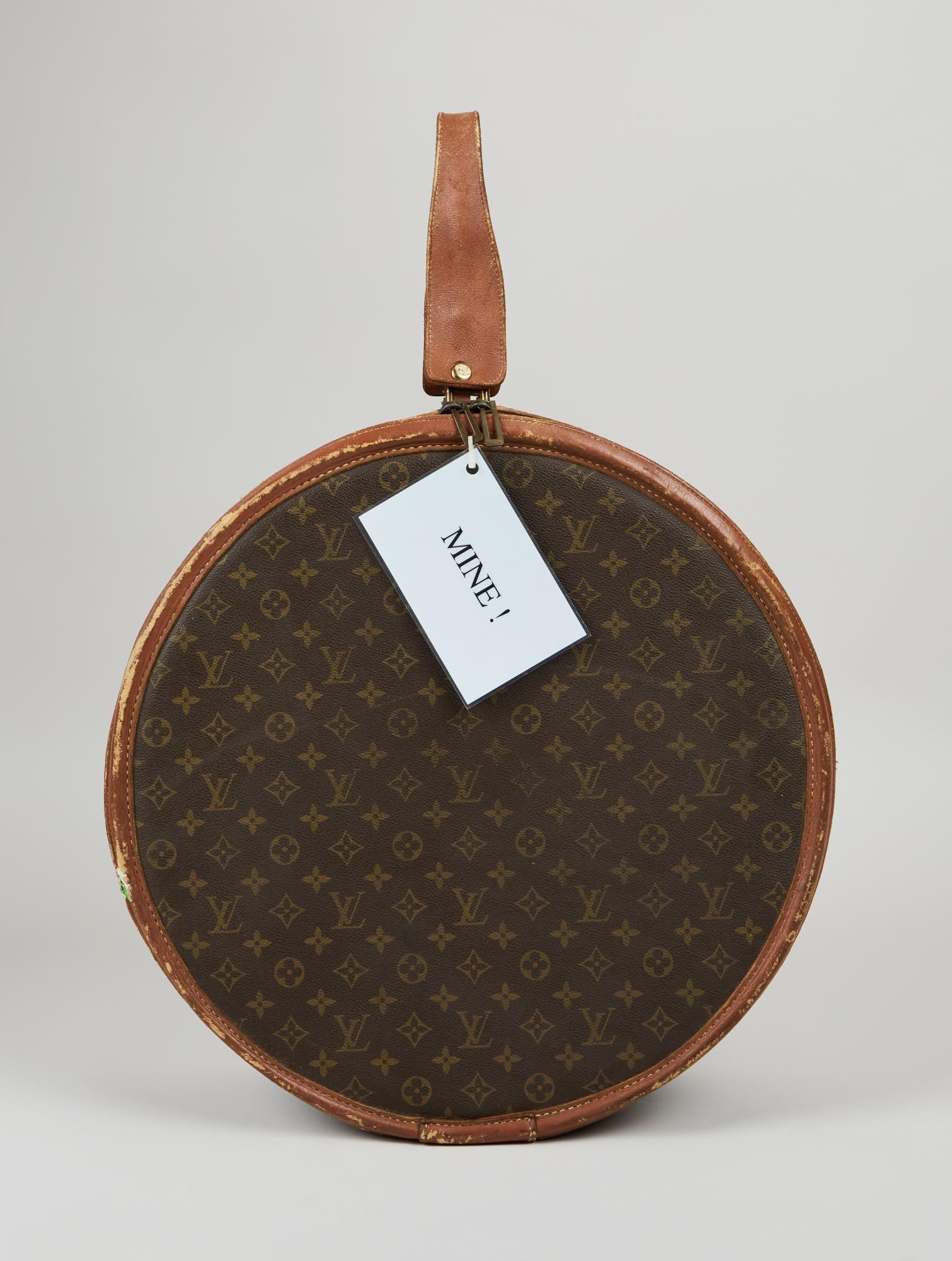 Lot #53. Elizabeth Taylor | Louis Vuitton Monogram Hat Box a round louis vuitton suitcase with a tag that says mine