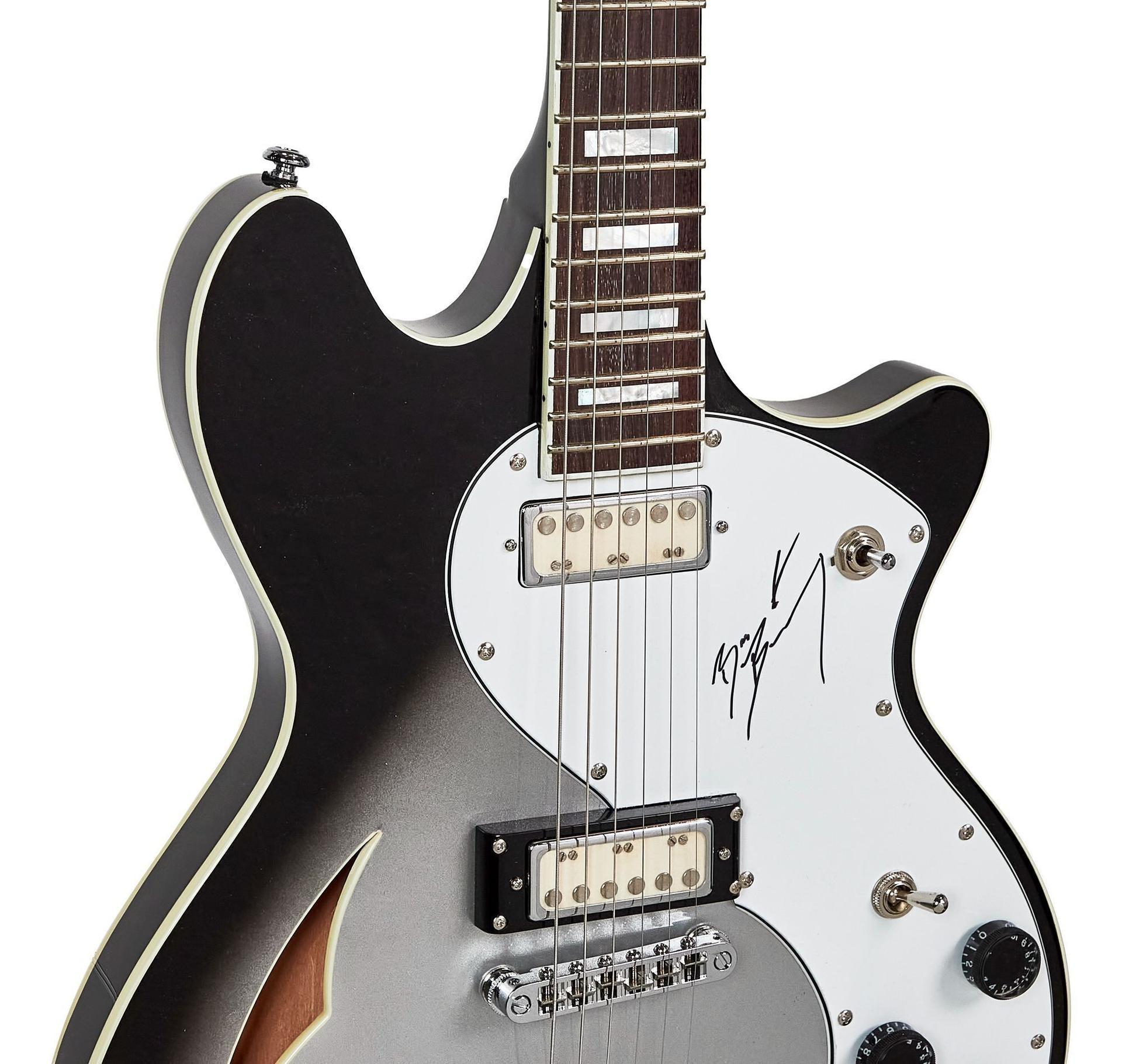 Black and silver semi-hollow electric guitar with a white pickguard signed in black.