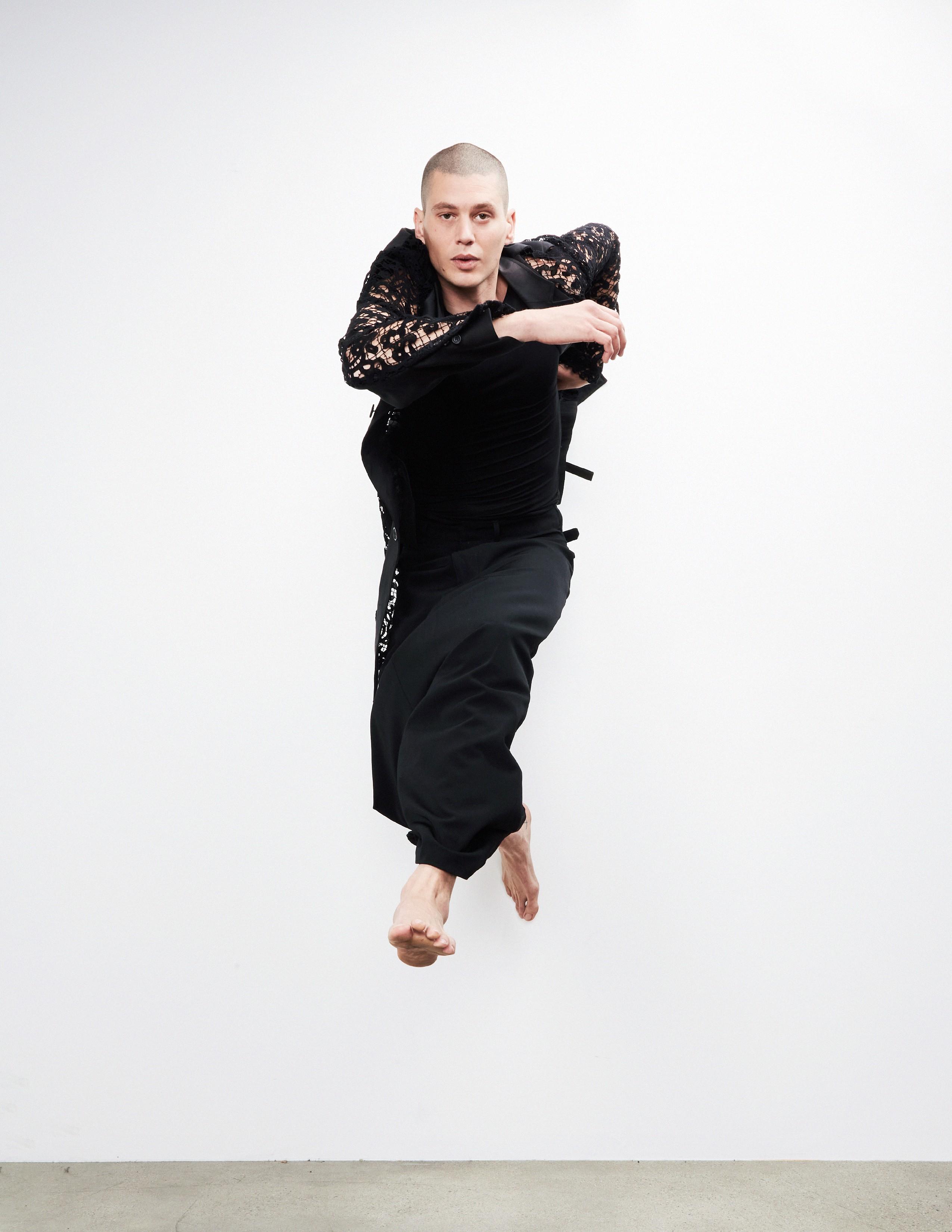 a man jumping while wearing a black suit